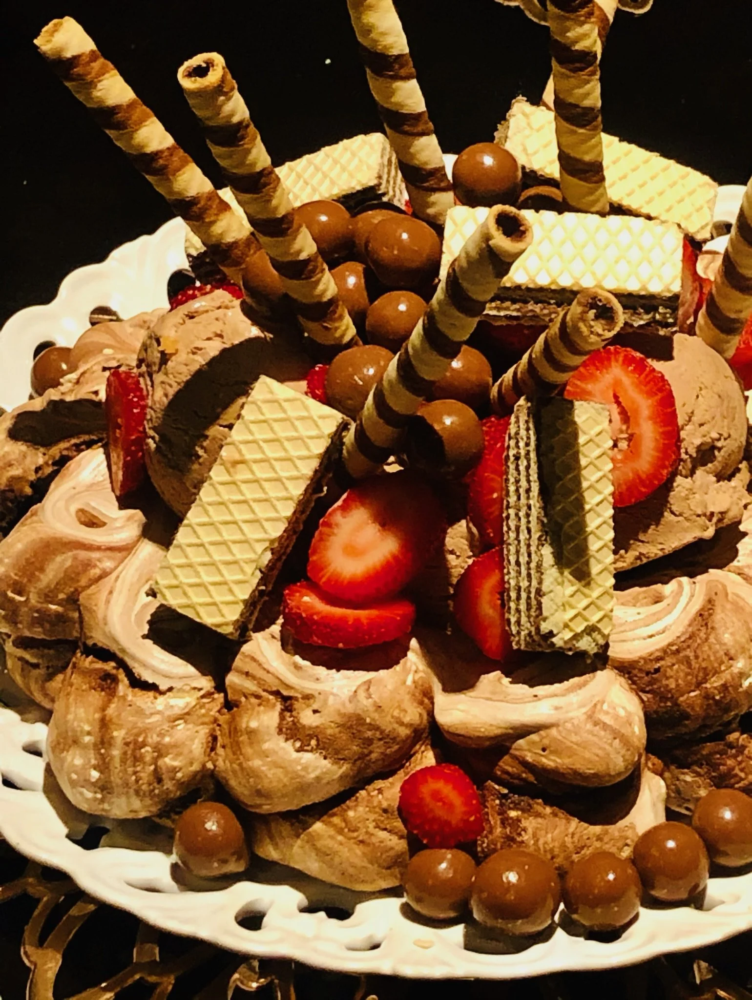 A decorated cake with strawberries, chocolate wafers, wafers, and chocolate candies.