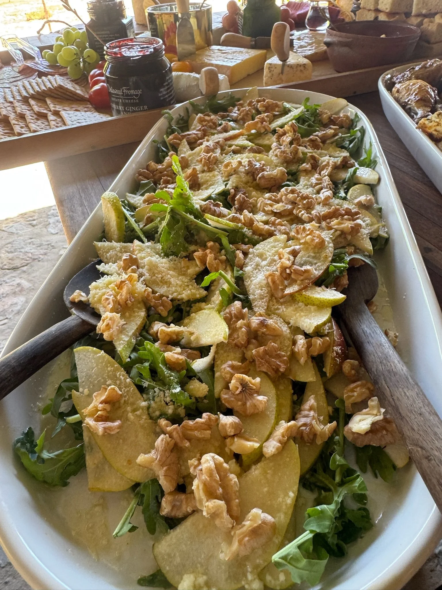 A pear, arugula, and walnut salad in a white serving dish.