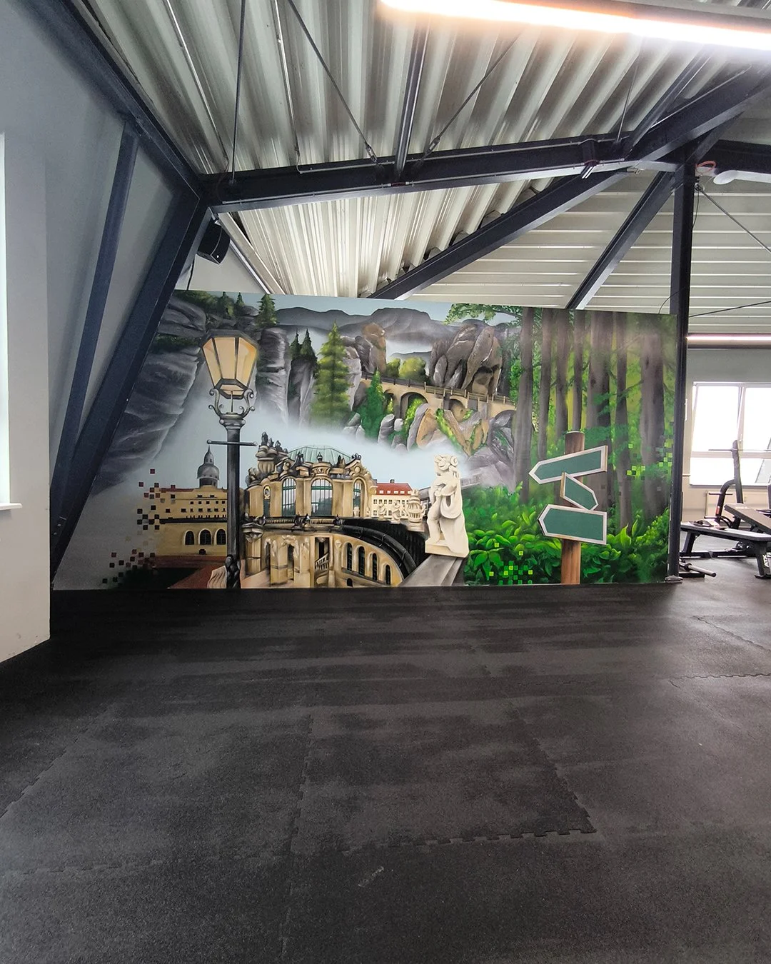 Graffiti Wand mit Landschaftsmotiv, Berge, Bäume, Brücke, Statue und Straßenwegweiser im Fitnessraum