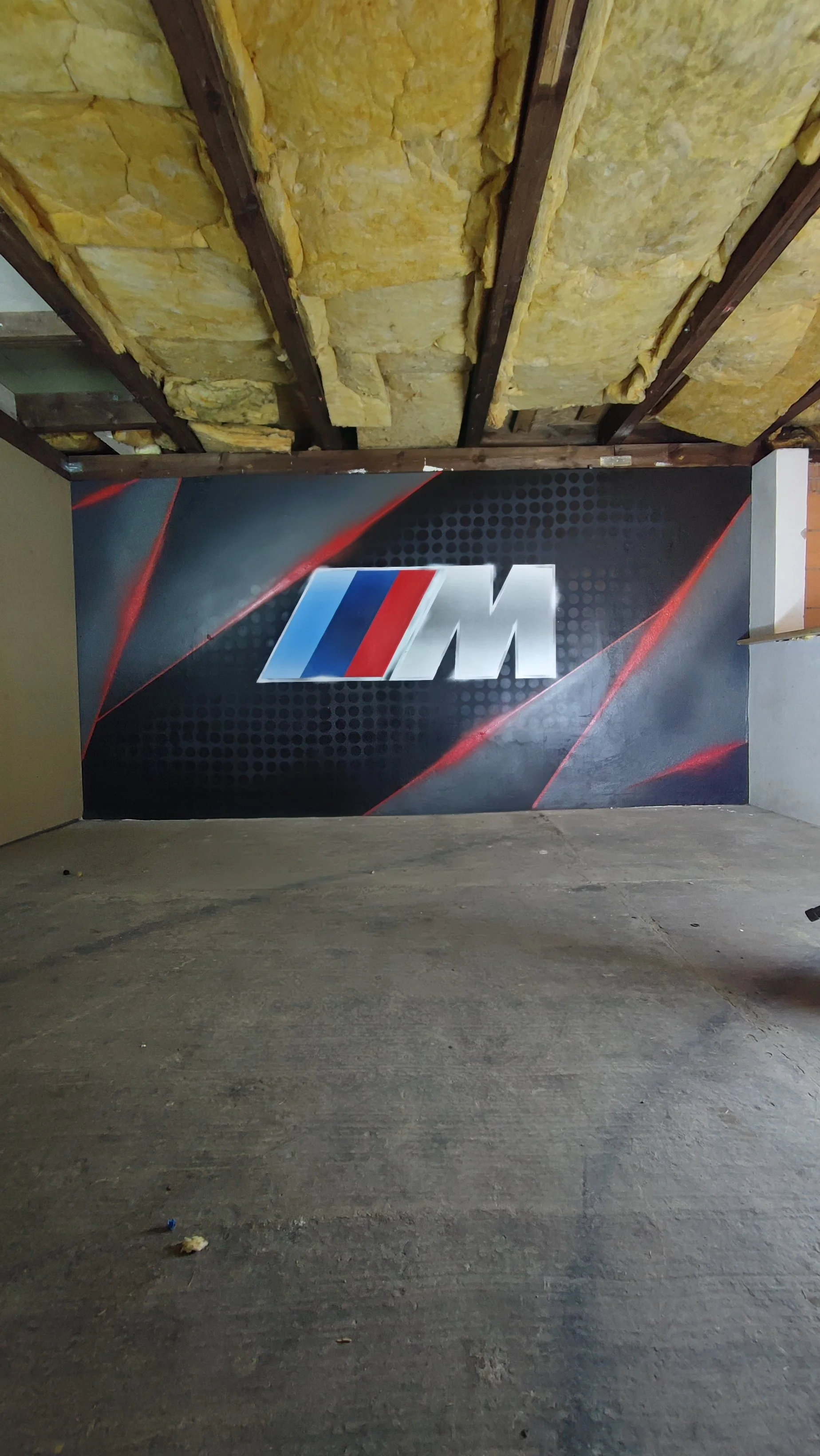 Innenraum eines Garagens mit BMW M Logo auf einer Wand.