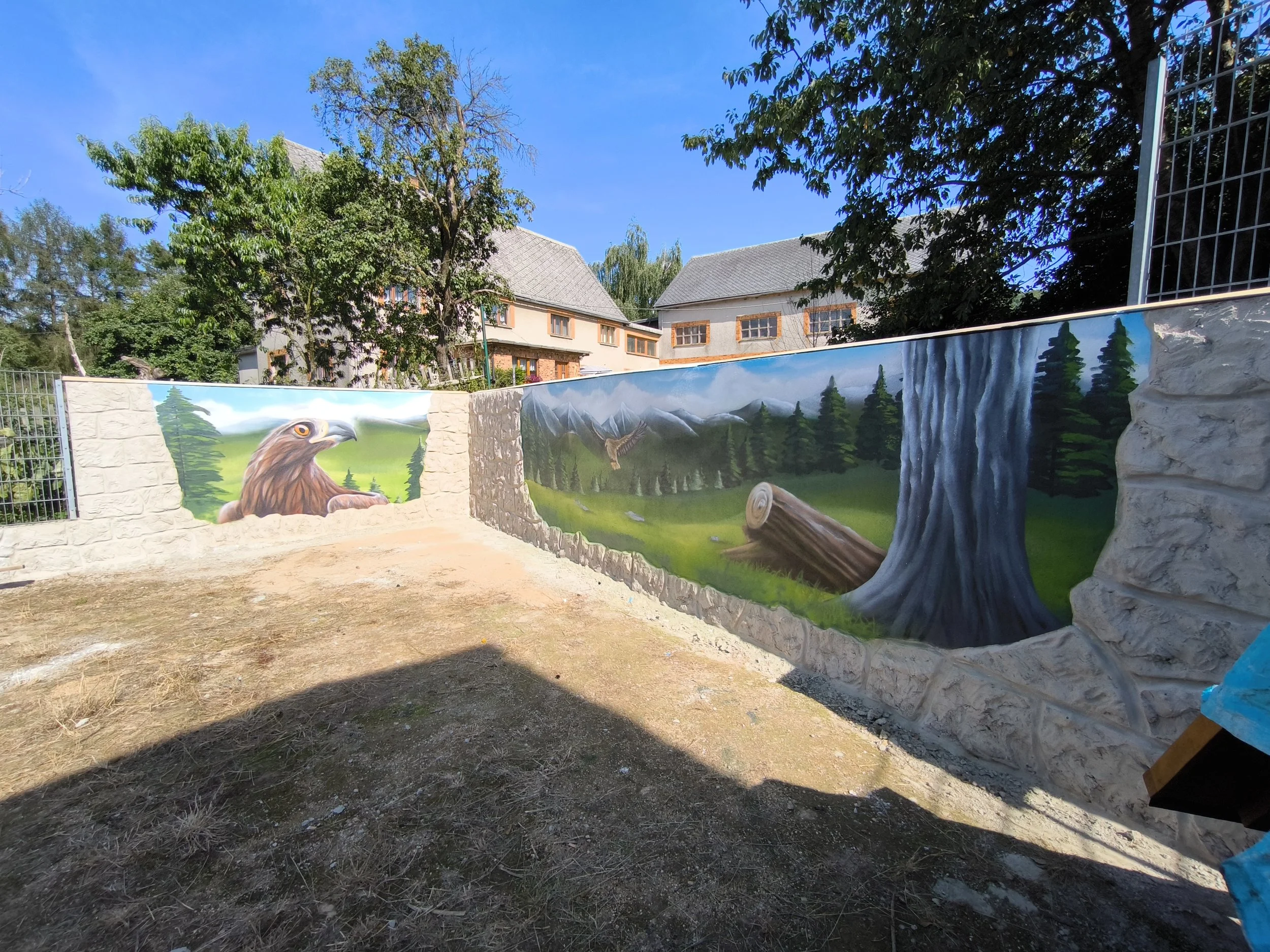 Mural mit Bergadler, Wald und Wasserfall auf einer Steinmauer im Freien