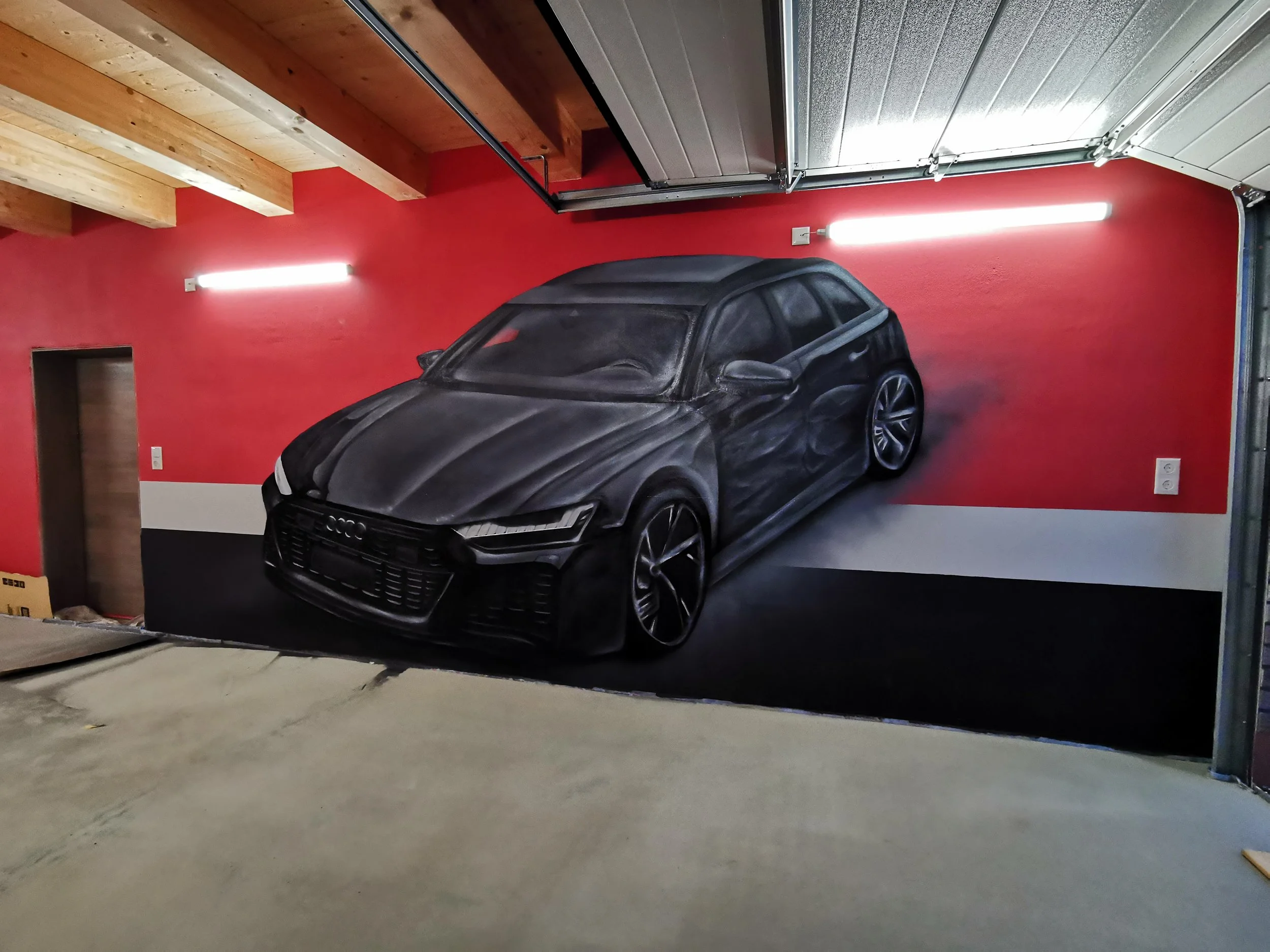 Wandgemälde eines schwarzen Autos, das an einer roten Wand in einer Garage gemalt ist.