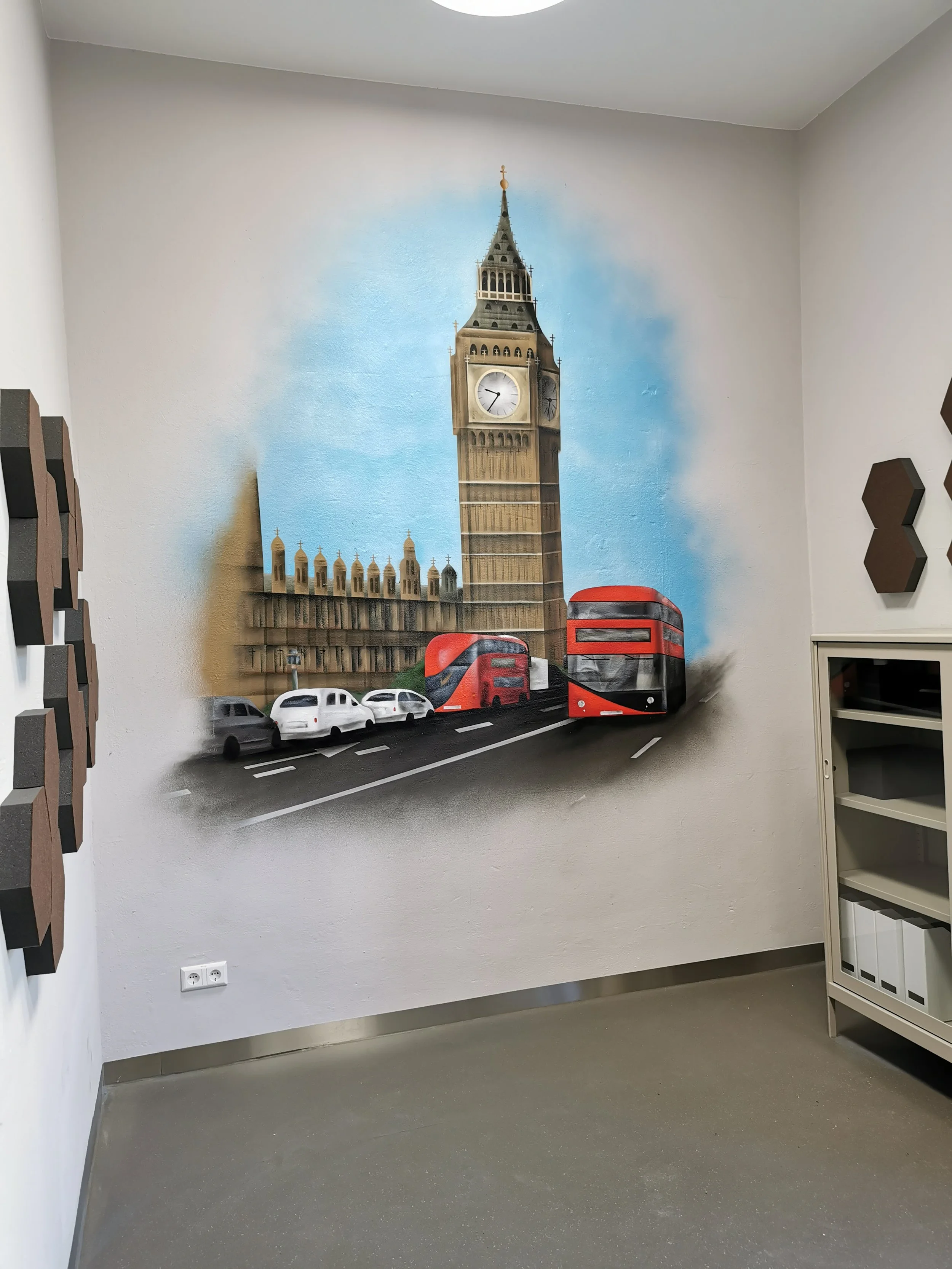 Wandmalerei im London-Thema mit Big Ben, roten Doppeldeckerbussen, alten Autos und blauer Himmel.