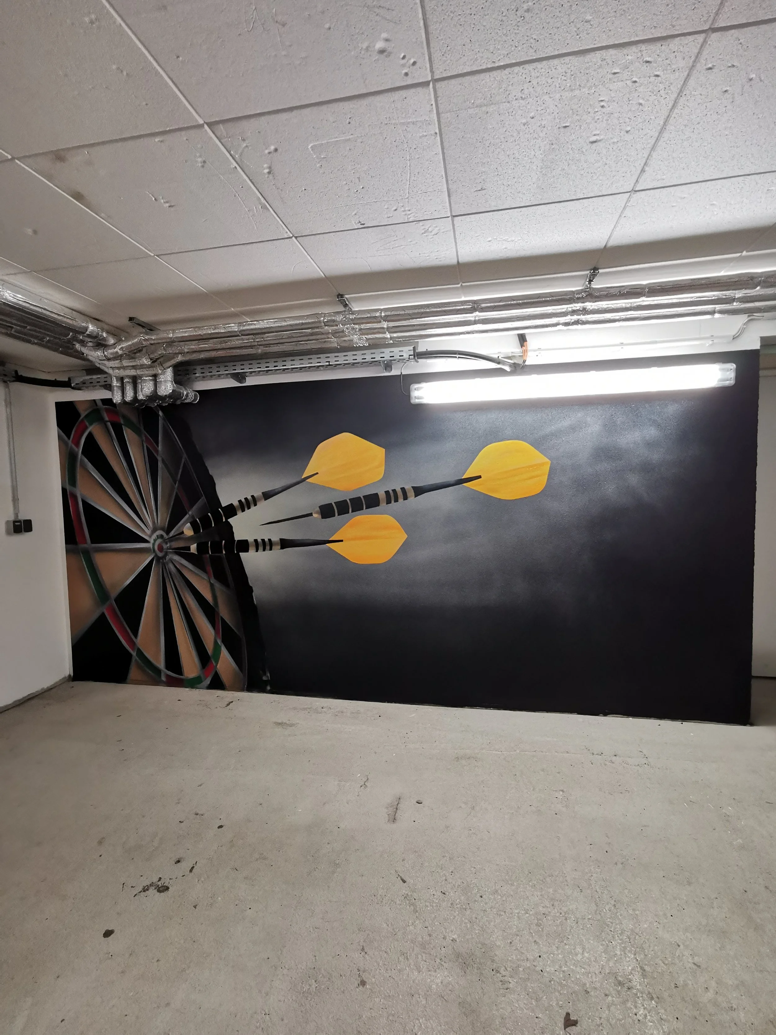 Wandmalerei mit Dartscheibe und drei gelben Darts auf schwarzem Hintergrund im Keller