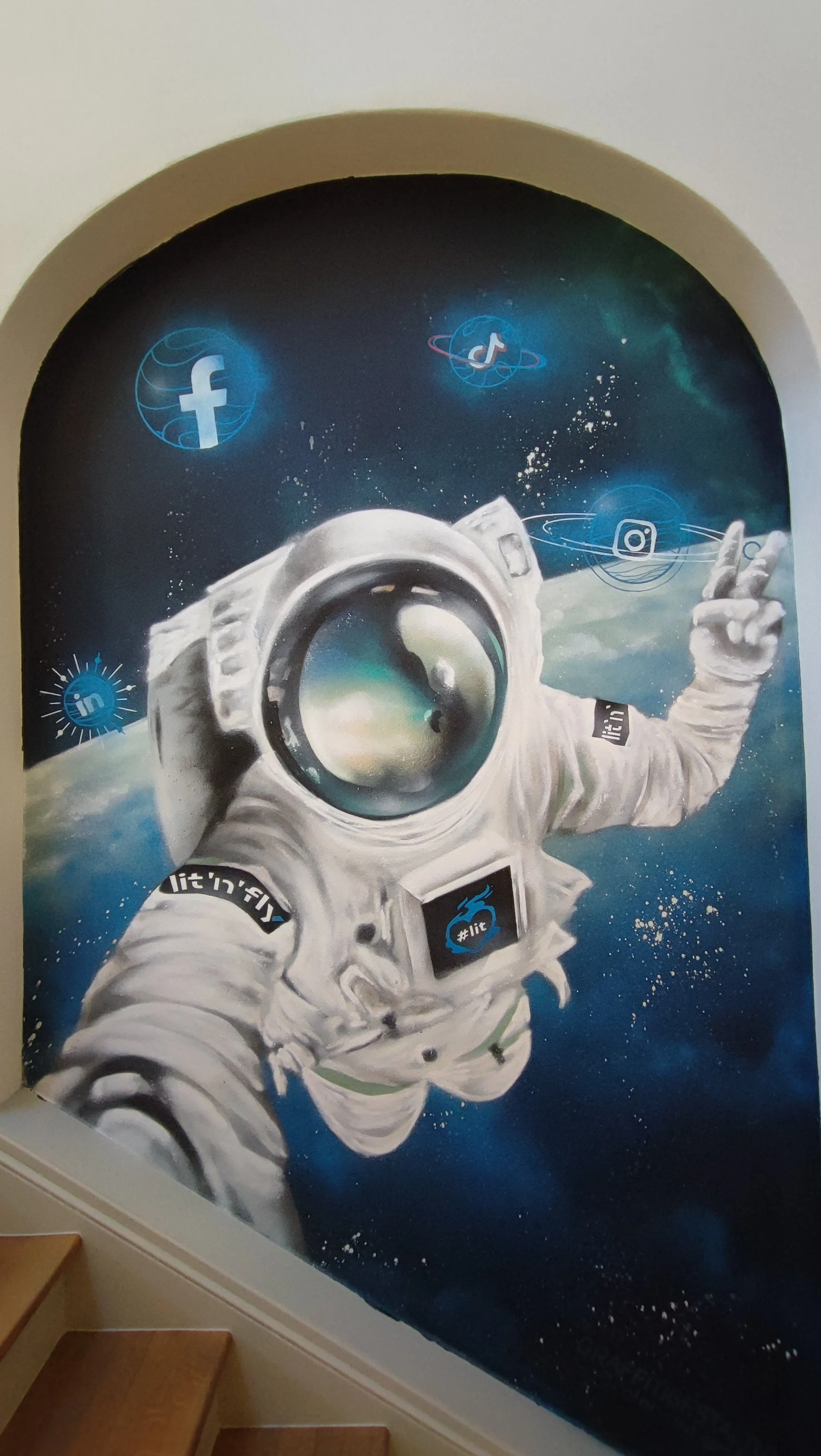 Graffiti eines Astronauten im All, der eine Hand mit dem Peace-Zeichen zeigt, umgeben von Social-Media-Logos wie Facebook, Instagram, TikTok, LinkedIn, YouTube und Twitter.