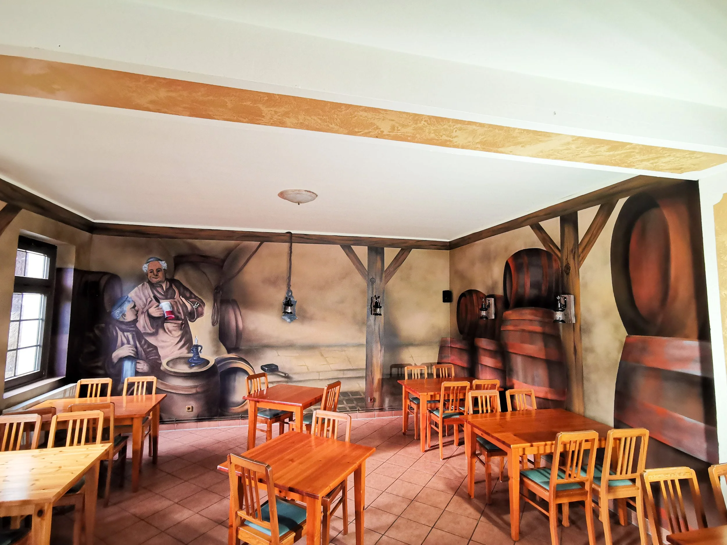 Ein Restaurant mit Wandgemälde eines Brauereivorführens, Holztischen und Stühlen.