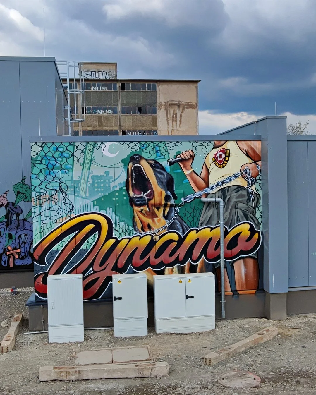 Straßenkunst mit einem großen, schreienden Hund, das Wort „Dynamix“ in auffälliger Schrift und ein Mensch mit einer Dose Sprayfarbe.