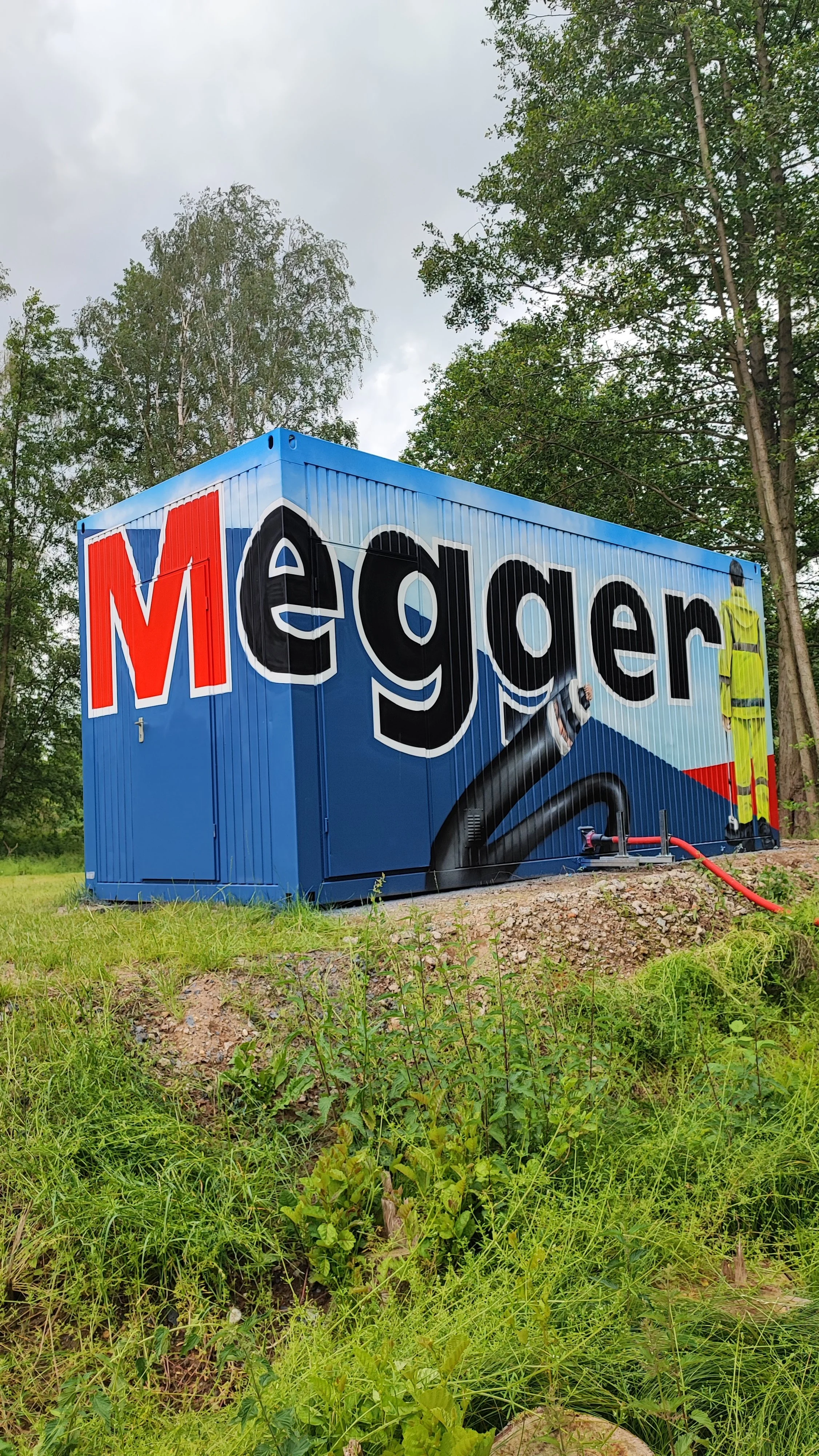 Graffiti auf einer blauen Containerwand mit graffiti-schreibschrift und einem Arbeiter in neonfarbener Kleidung.