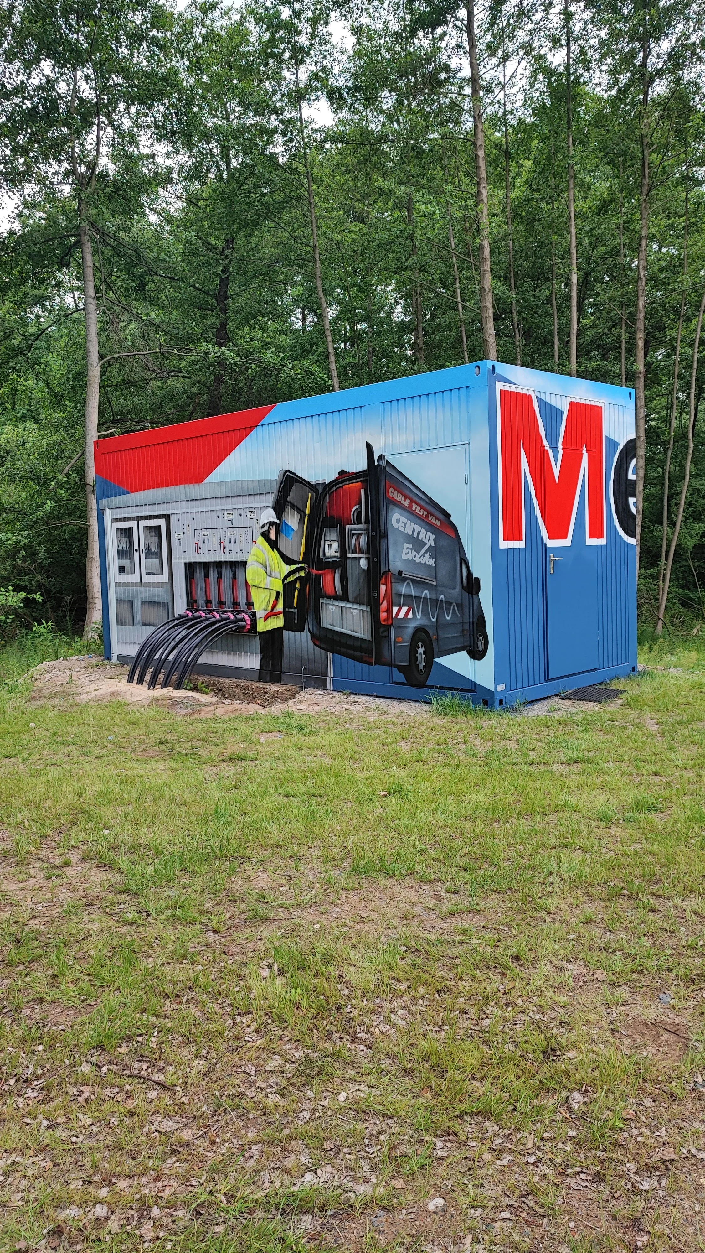 Graffiti auf einer grünen Wand mit einem Installationsbild eines Technikers, der Kabel an einer roten Werkzeugtasche an einer elektrischen Anlage anschließt.