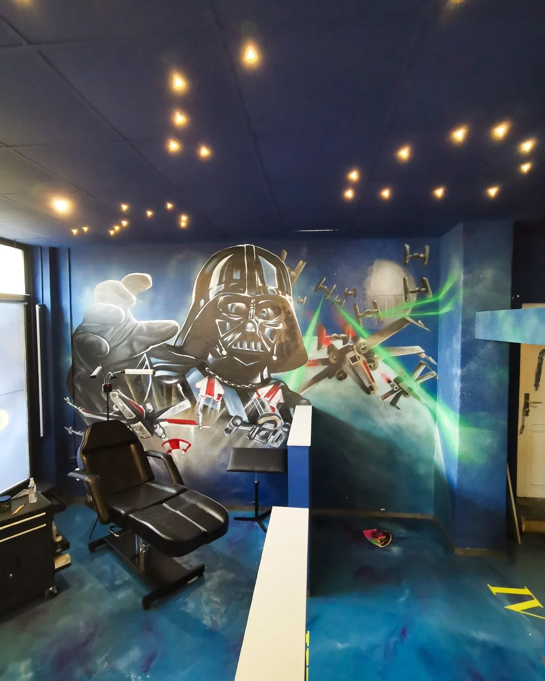 Star Wars-Malerei an einer Wand mit Darth Vader, der eine Hand ausstreckt, und TIE Fighters, die in den Weltraum fliegen, mit grünen Laserstrahlen und einer großen Planeten im Hintergrund.