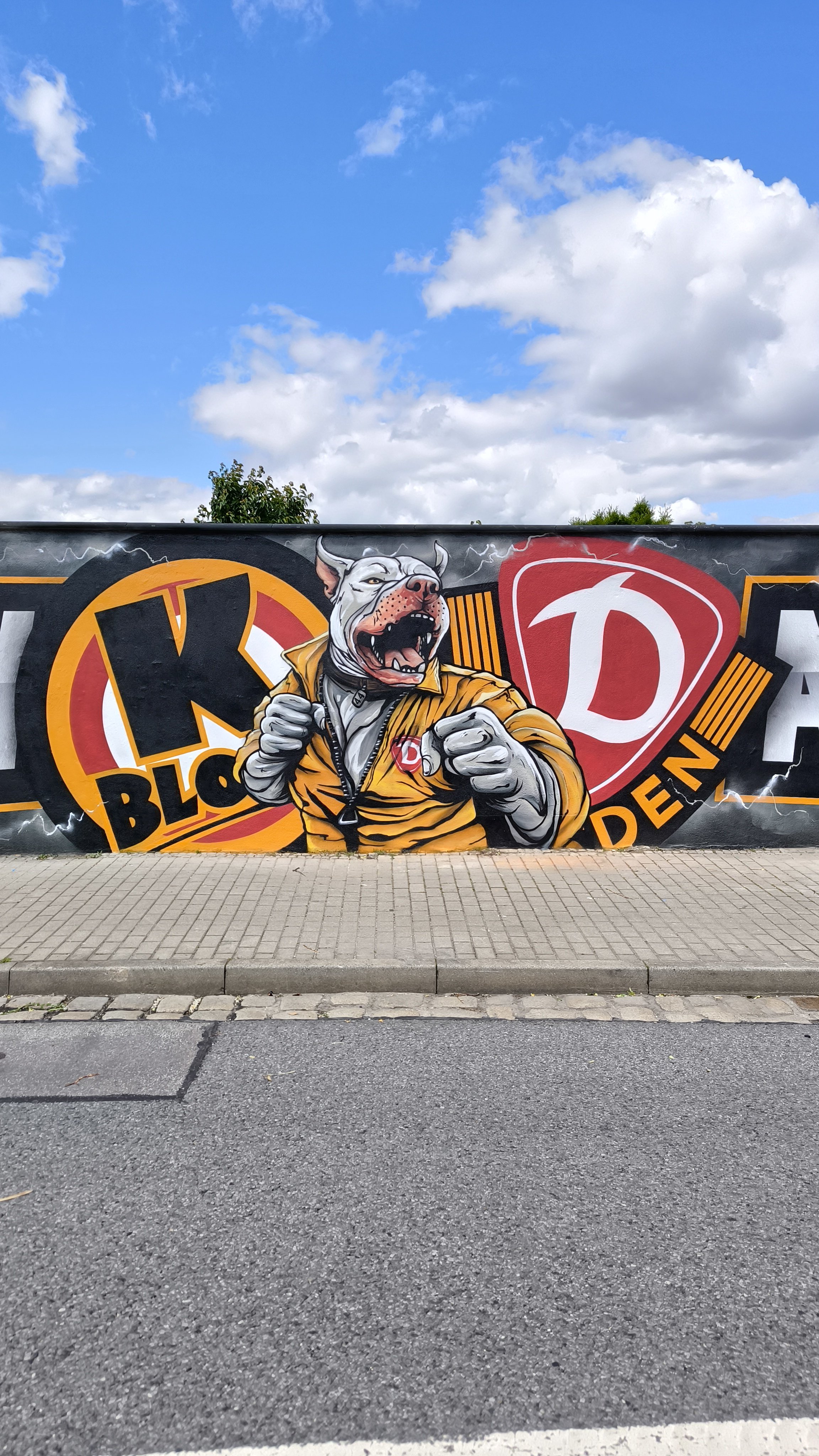 Grafitti eines kampfbereiten Hundes mit blauer Himmel im Hintergrund.