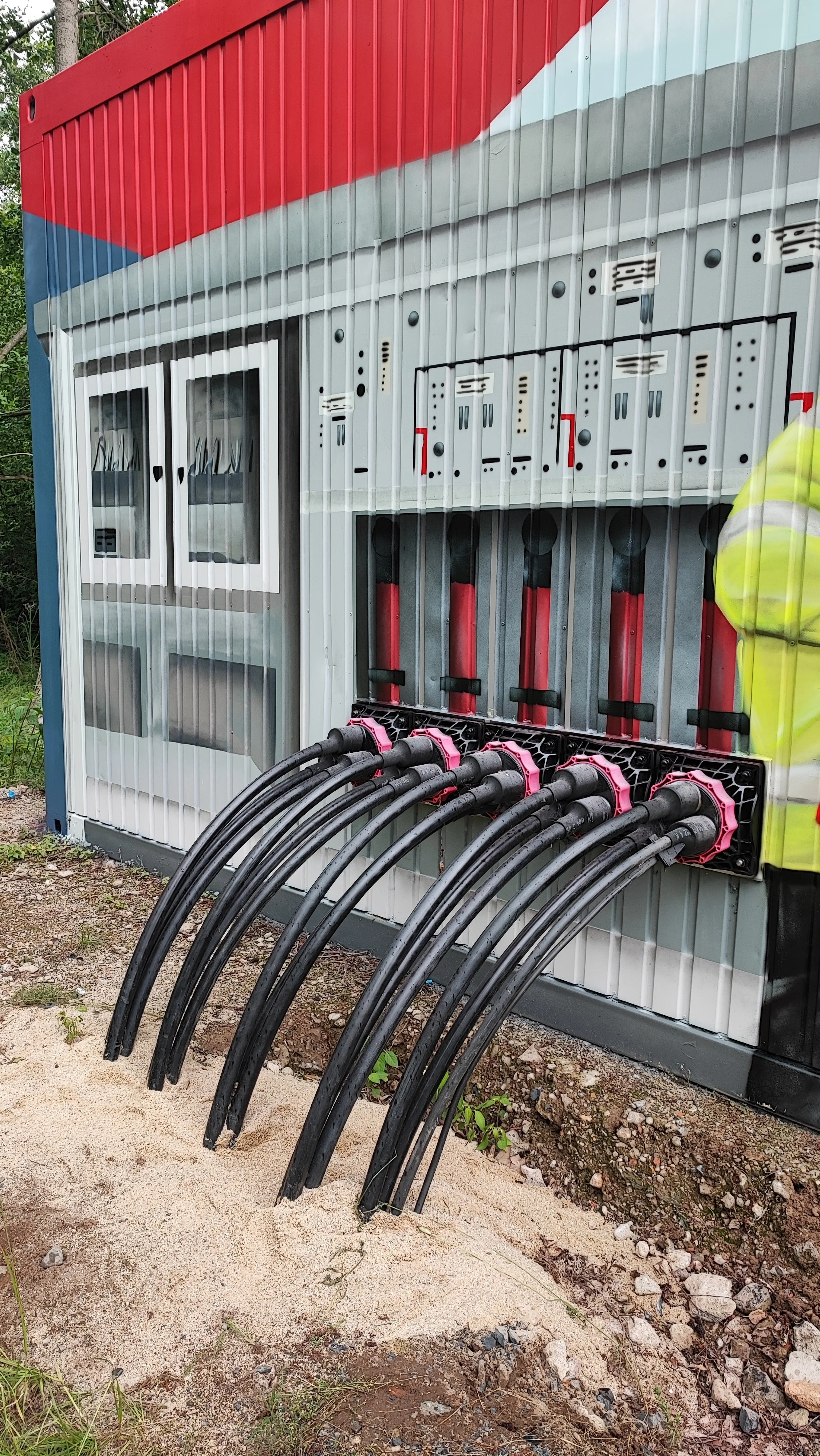 Fehlerstromschutzschalter mit mehreren Kabeln, in einem rot, weiß, grau und schwarz gestalteten Elektronik- und Steuerungskasten auf einem Erdgeschoss installiert.