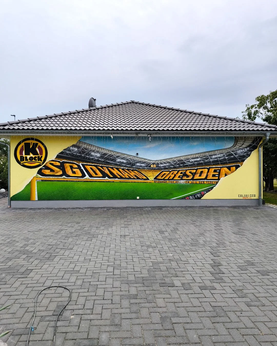 Mauerbemalung eines Fußballstadions mit der Aufschrift "SG Dynamo Dresden", einer Mannschaftsnummer und einem Stadion im Hintergrund.
