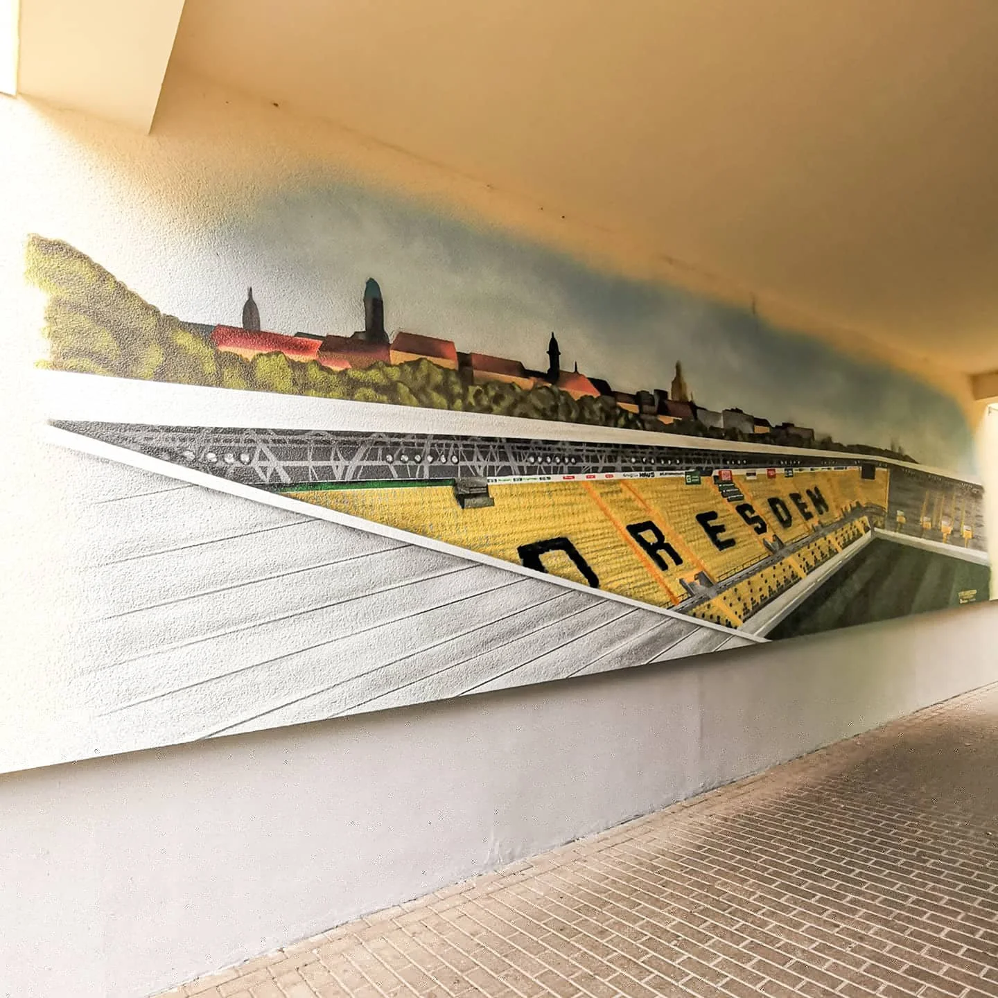 Wandgemälde eines Stadthorizonts mit Kirchen auf einer Mauer an einer Straße.