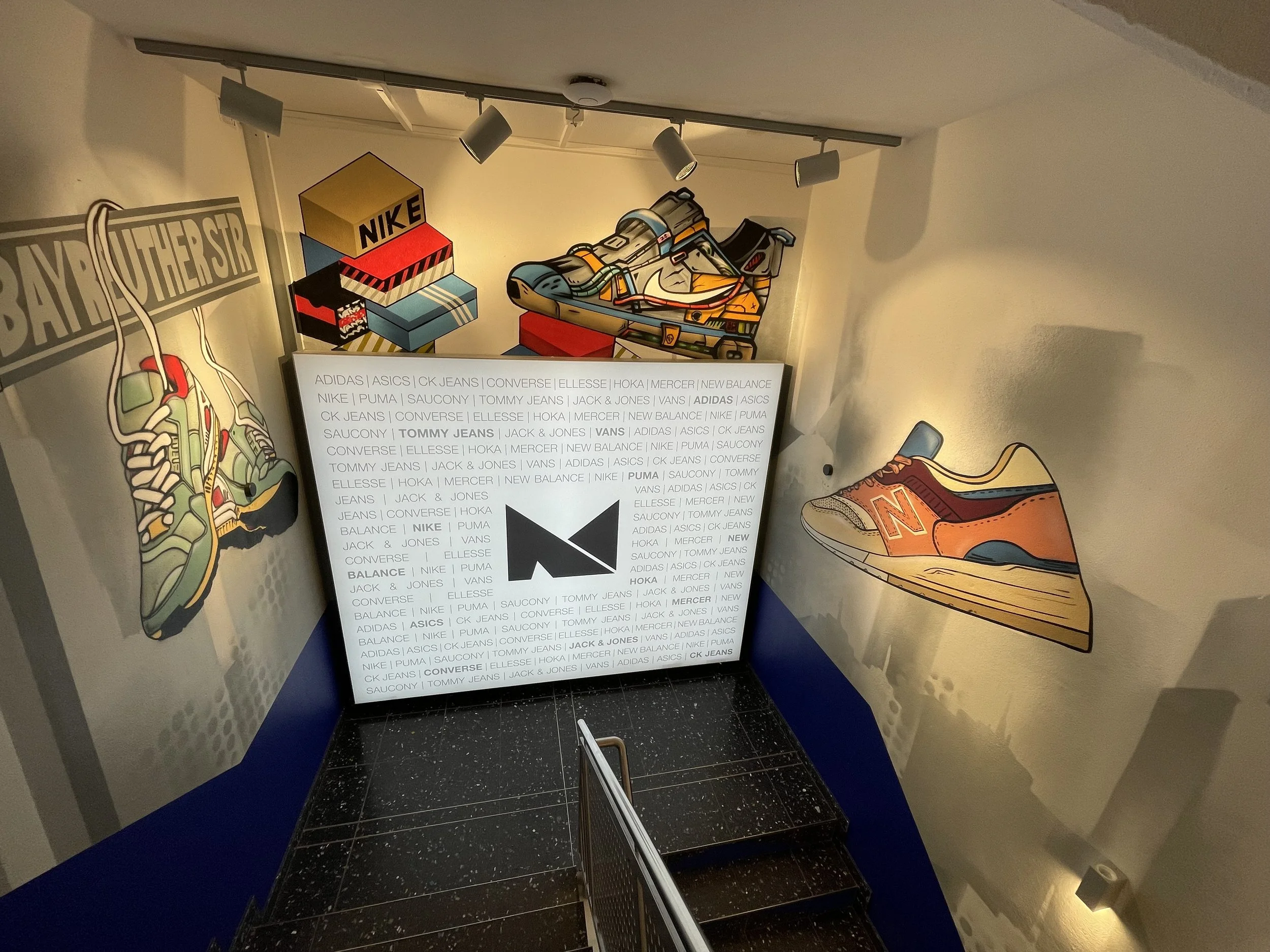 Wand mit Graffiti und Umschriften verschiedener Sportswear- und Schuhmarken wie Nike, Adidas, Puma beim Eingang eines Hauses