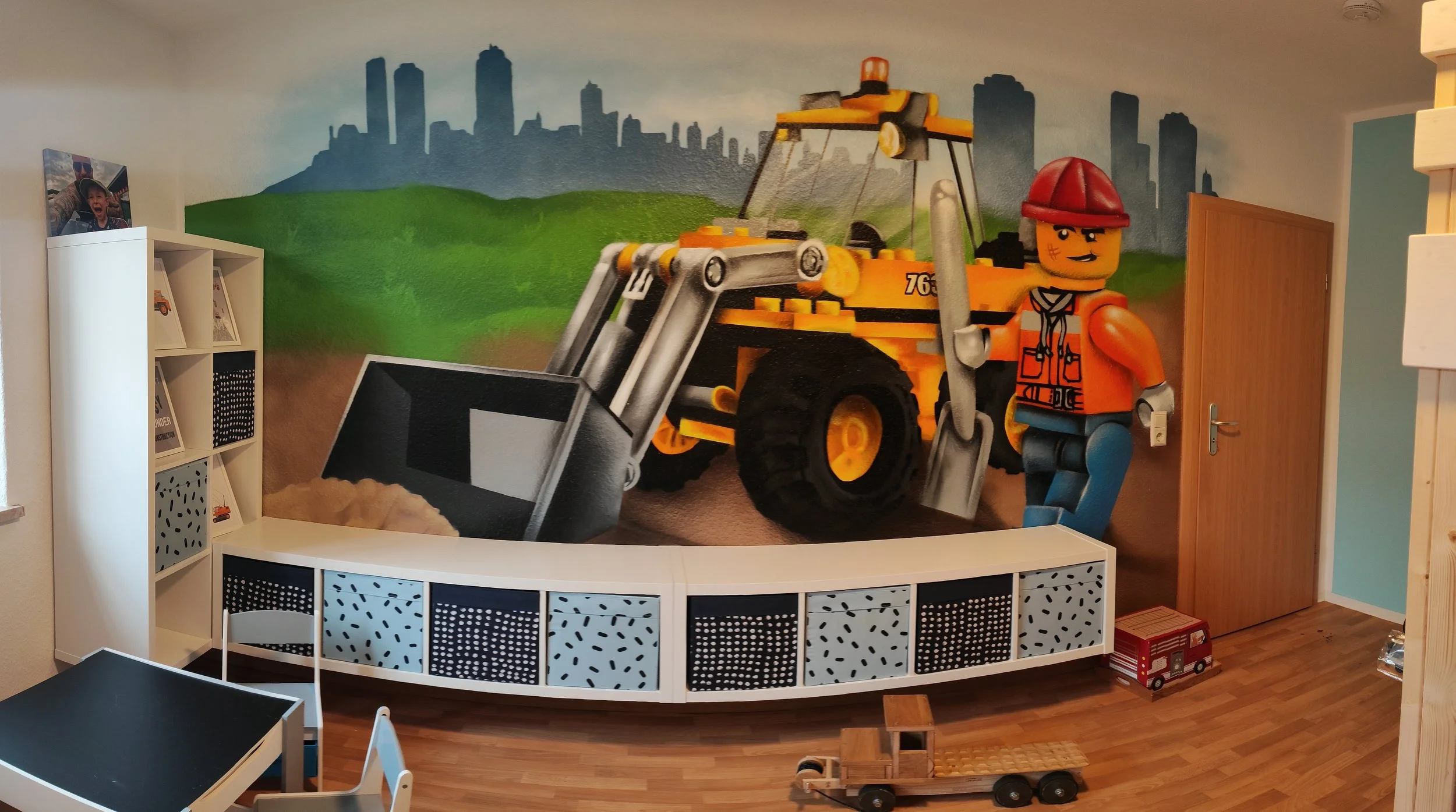 Wandmalerei in einem Kinderzimmer mit Baufahrzeug und Bauarbeiter-LEGO-Figur.