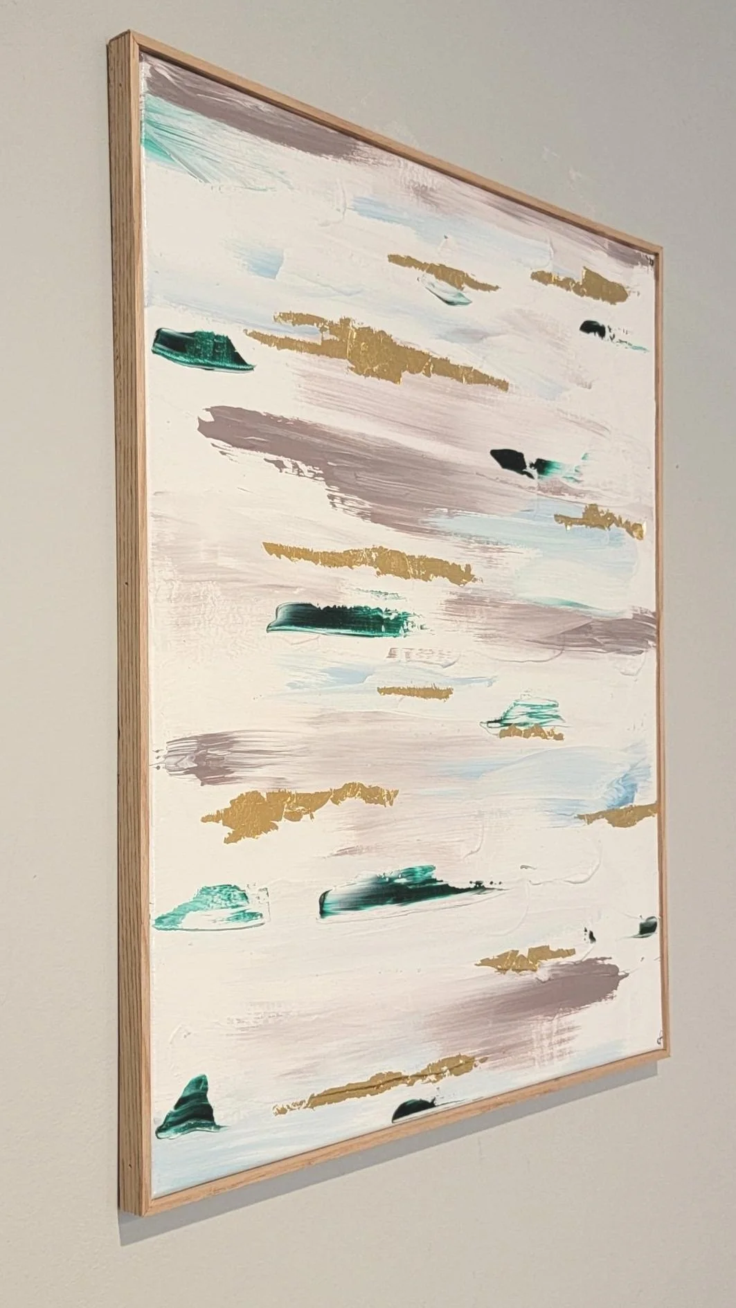 Abstract painting with horizontal brush strokes in green, gold, gray, and cream, mounted in a wooden frame.