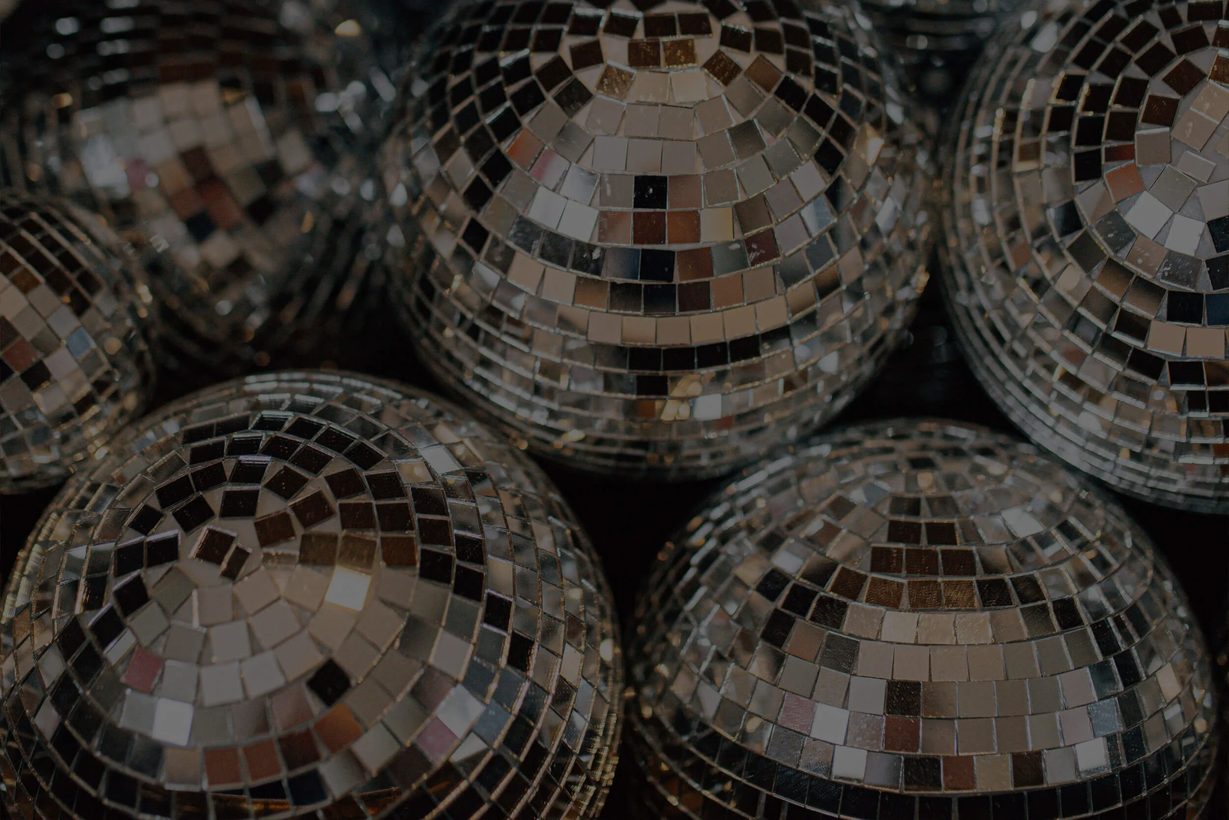 Multiple disco balls with mirrored mosaic surfaces stacked together.