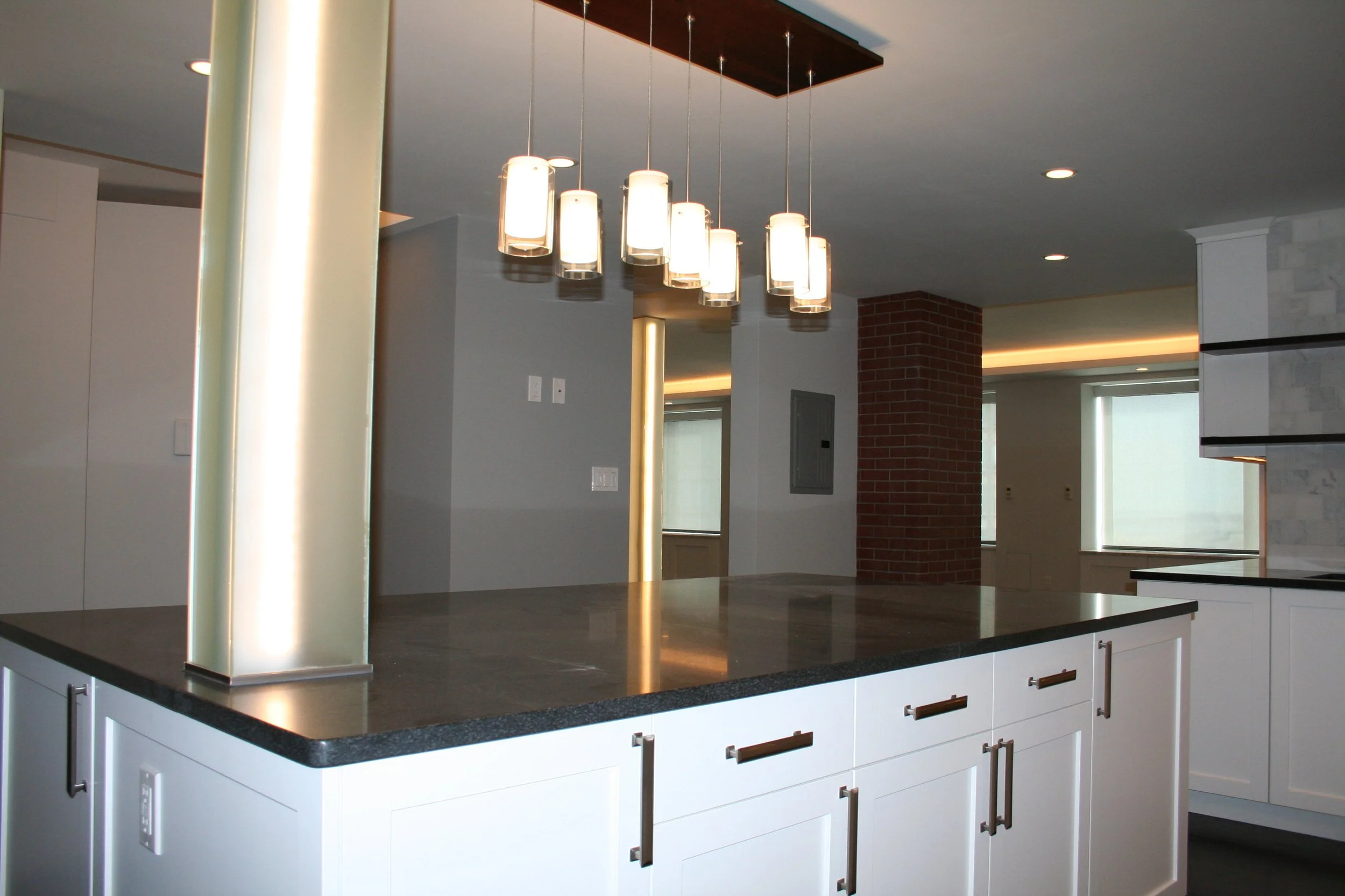 Modern kitchen with a large island, white cabinets, and a pendant light fixture with multiple lights hanging from the ceiling.
