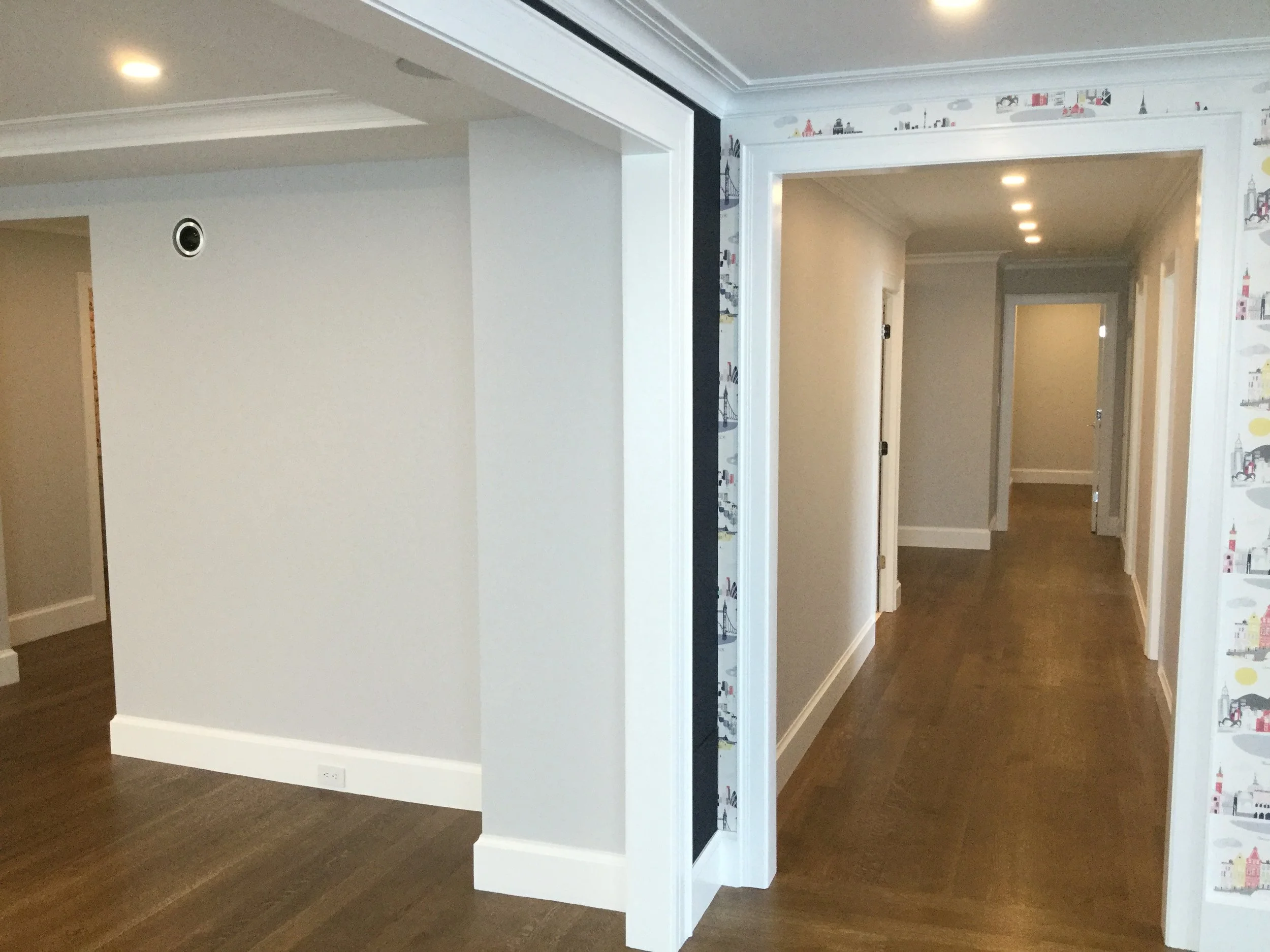 Empty corridor with white walls and wooden flooring in a residential interior
