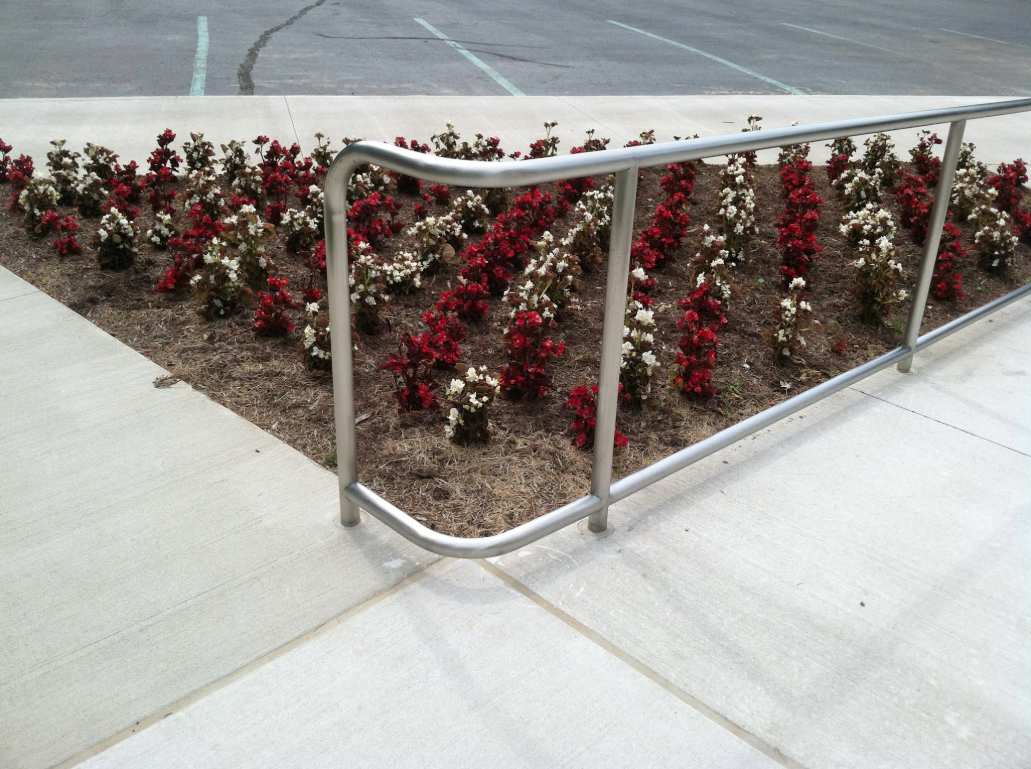 Low‑profile steel guardrails providing edge protection along landscaped areas adjacent to pedestrian walkways.