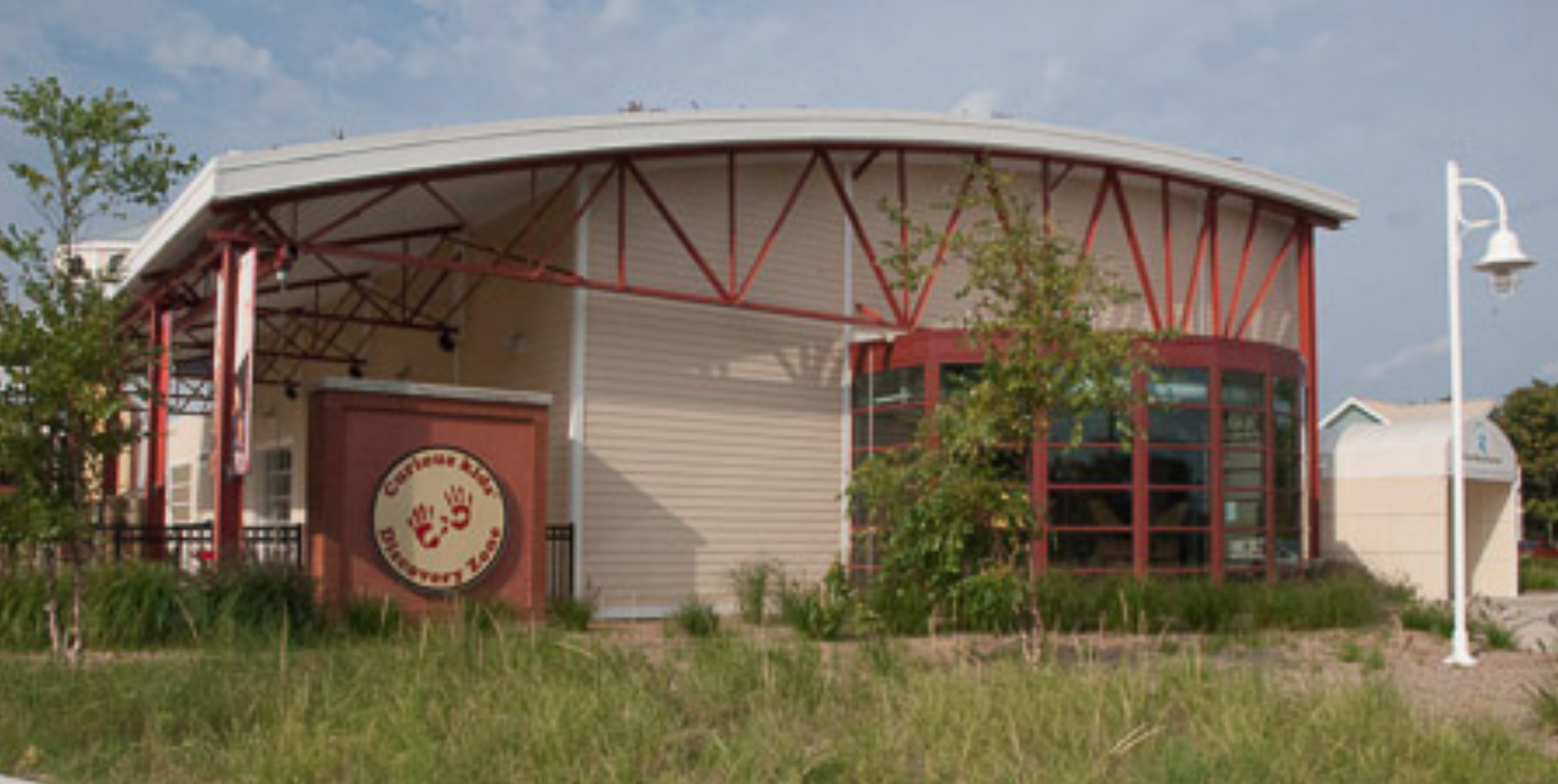Curved Steel Canopy and Structural Framing at the Curious Kids' Discovery Zone, Providing Covered Exterior Space and Architectural Definition. 