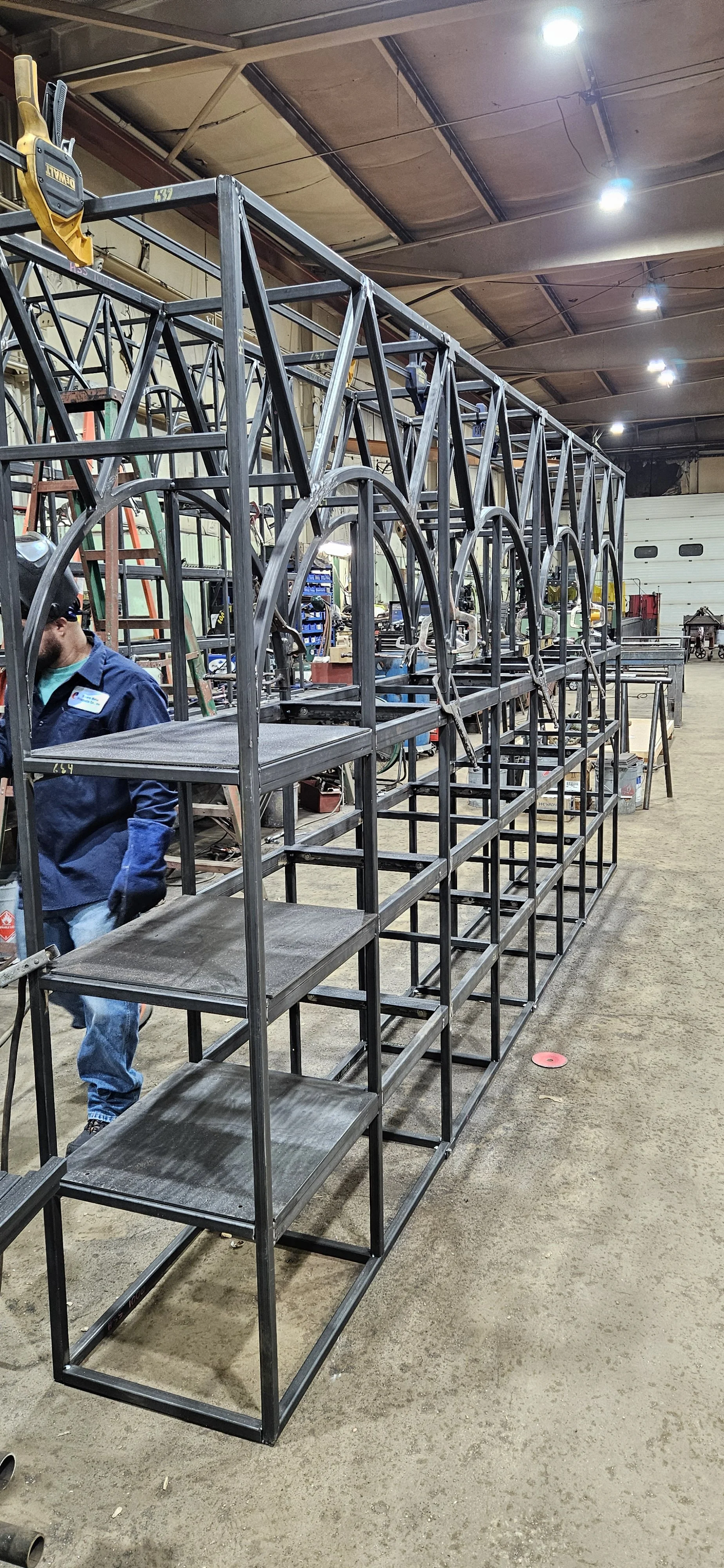 Fabricated steel framework with curved architectural openings during shop fabrication.
