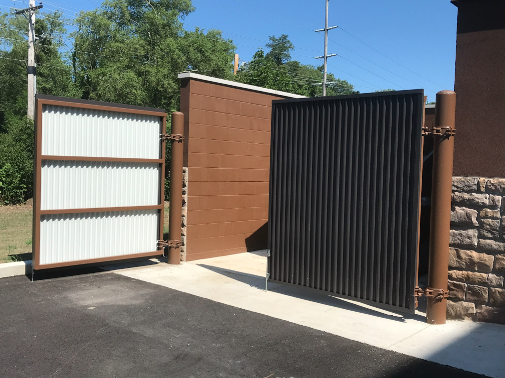 Custom fabricated sliding metal gate system installed between masonry walls.