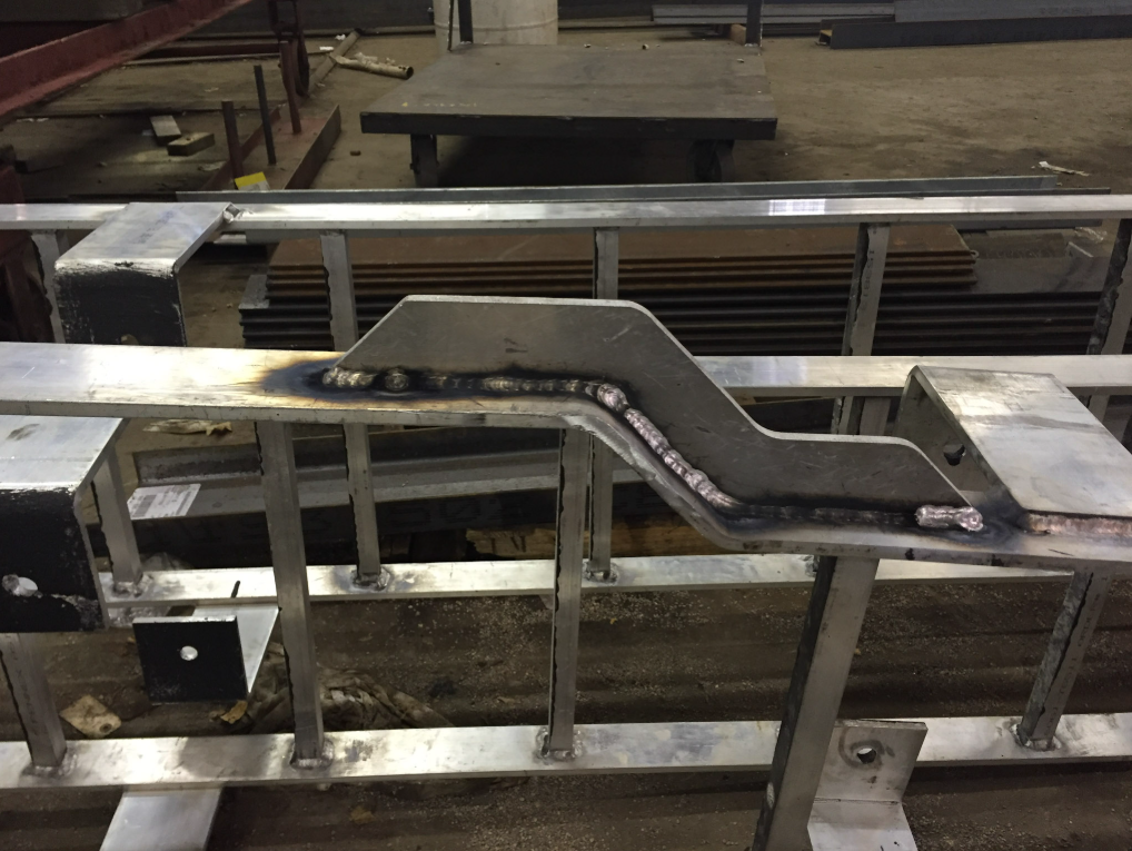 Fabricated steel component staged on workbench in fabrication shop.