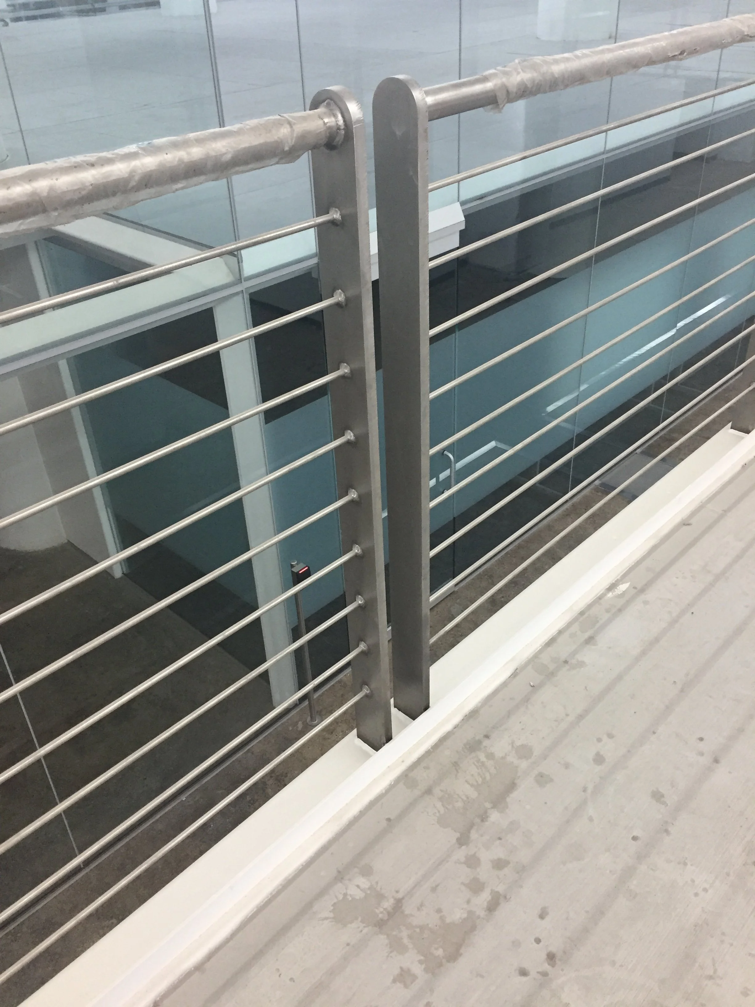 Custom Stainless Steel Cable Railing System Fabricated for Elevated Interior Walkways.