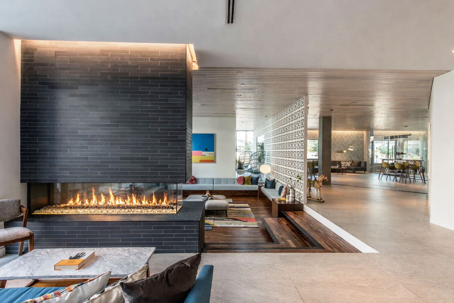 Modern living room with fireplace, abstract painting, and seating area.