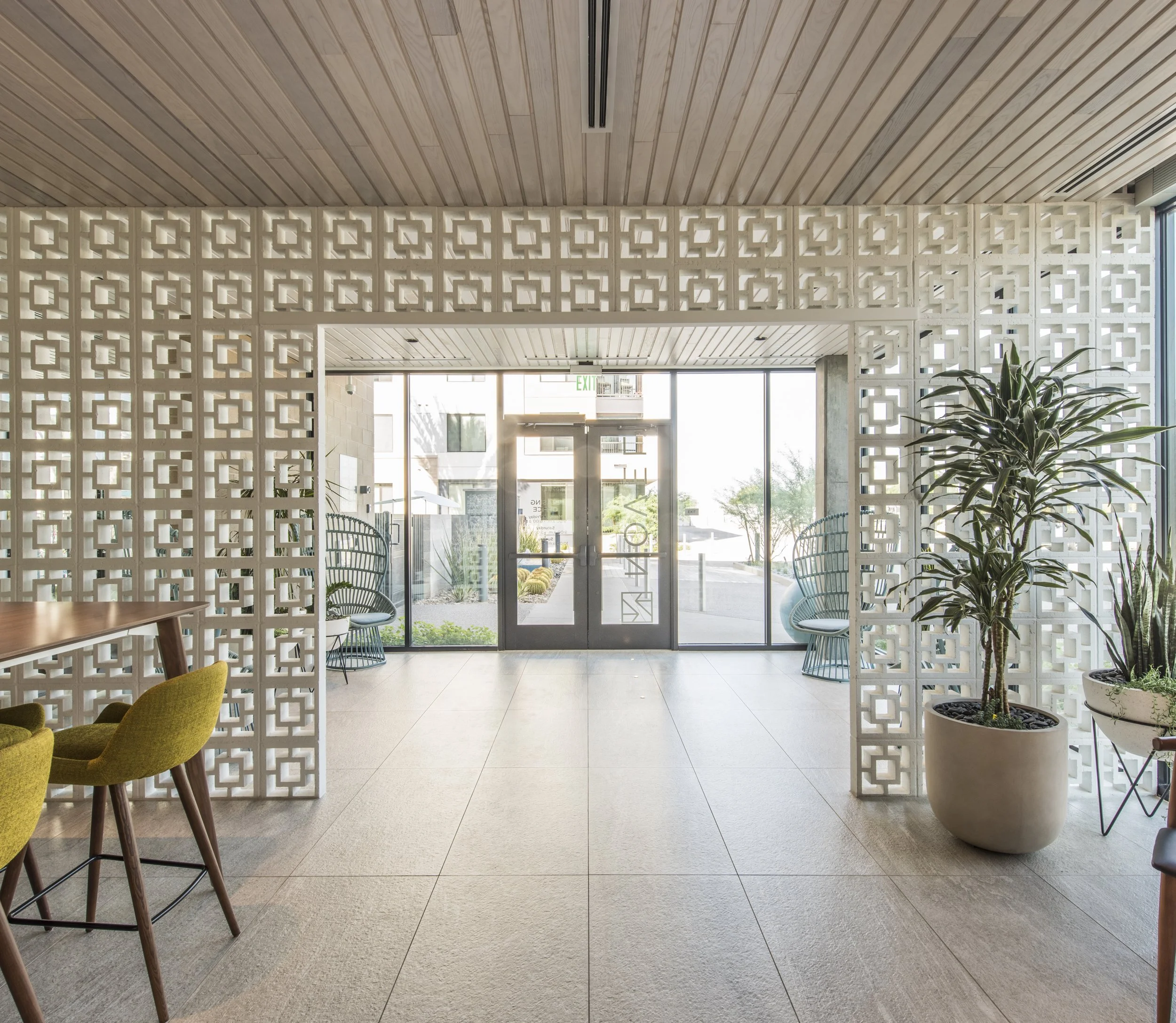 Modern lobby with lattice wall, glass doors, and potted plants.