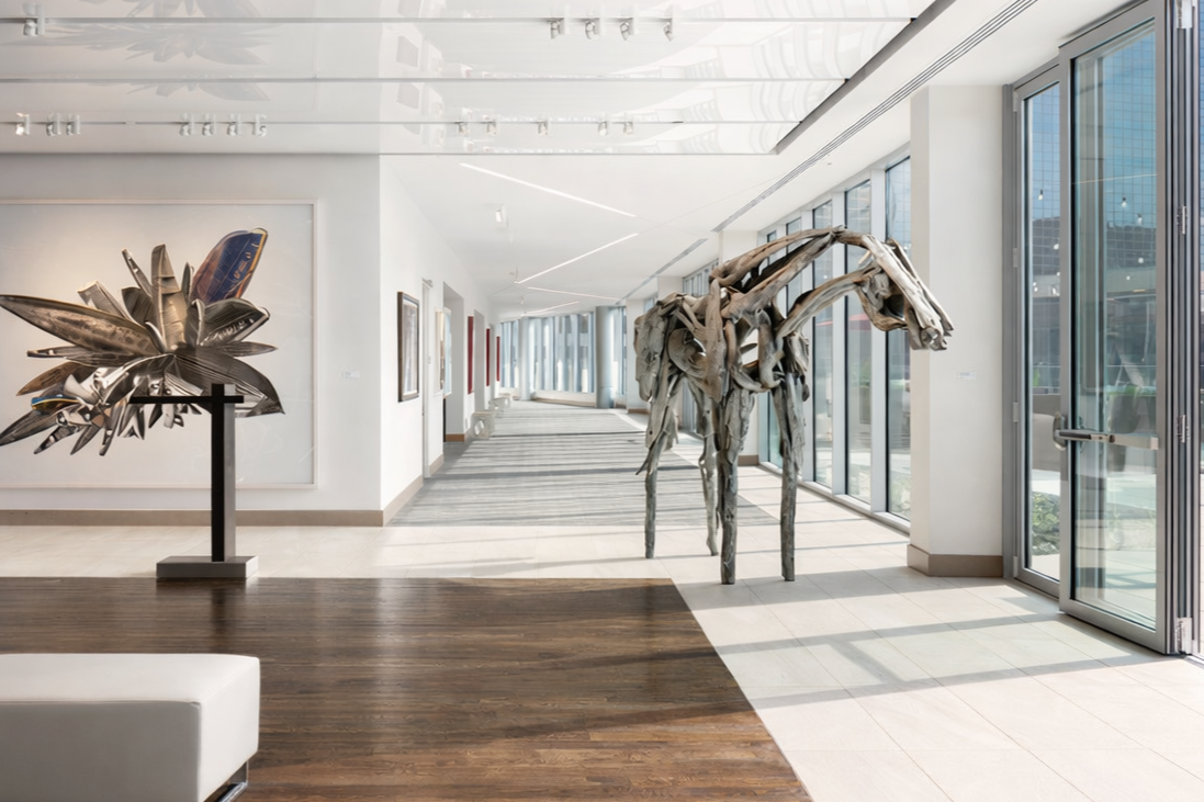 Art gallery interior featuring a sculptural installation of a horse and abstract artwork on the wall