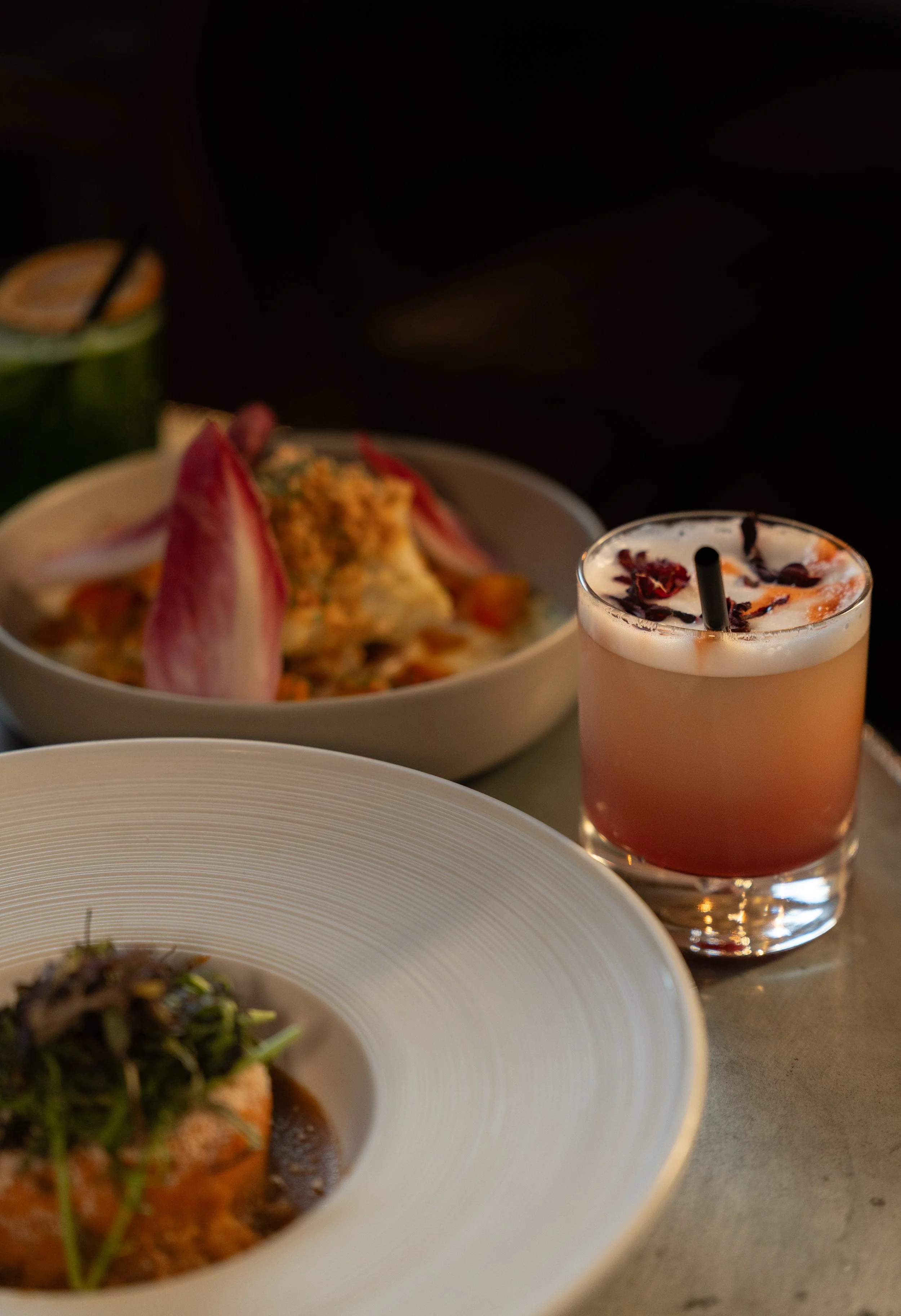 Assiette de plat principal, salade et cocktail dans un dîner élégant.
