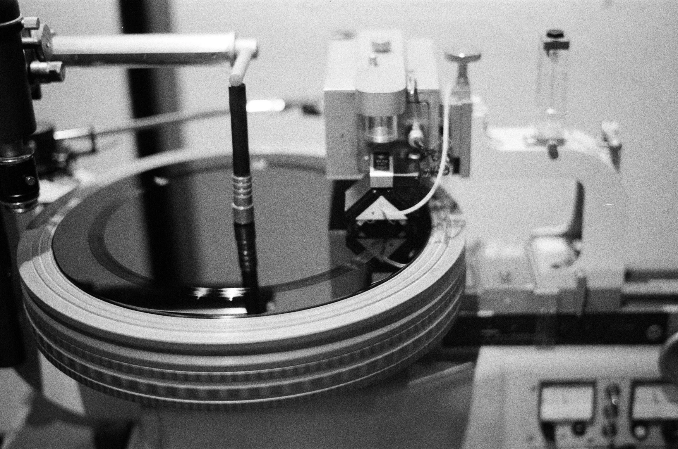Close-up of a scientific instrument or machinery with circular metallic parts, wires, and electronic components in black and white.