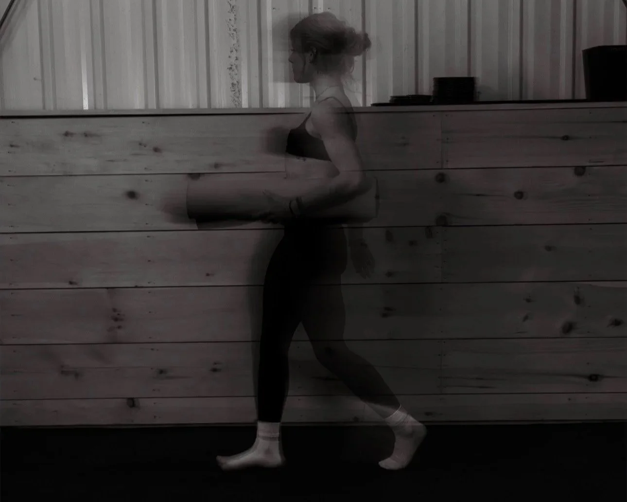 A woman practicing yoga in a room with wooden paneling, captured in a motion-blur photo.