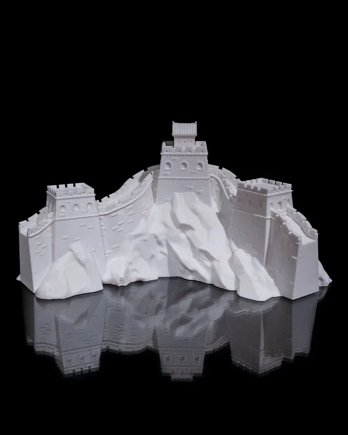 White model of the Great Wall of China with watchtower structures, reflected on a black surface.