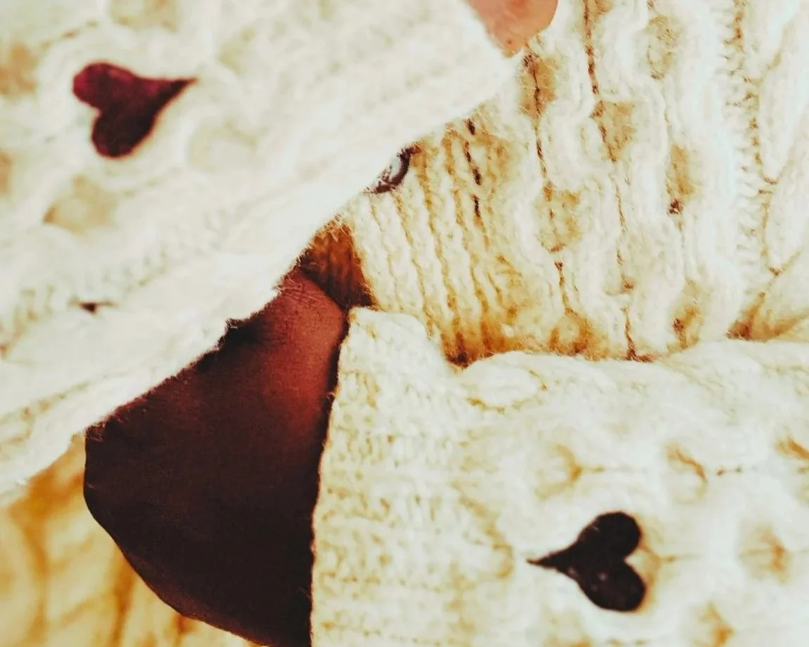 Close-up of a piece of creamy, textured fabric with red hearts on sleeve