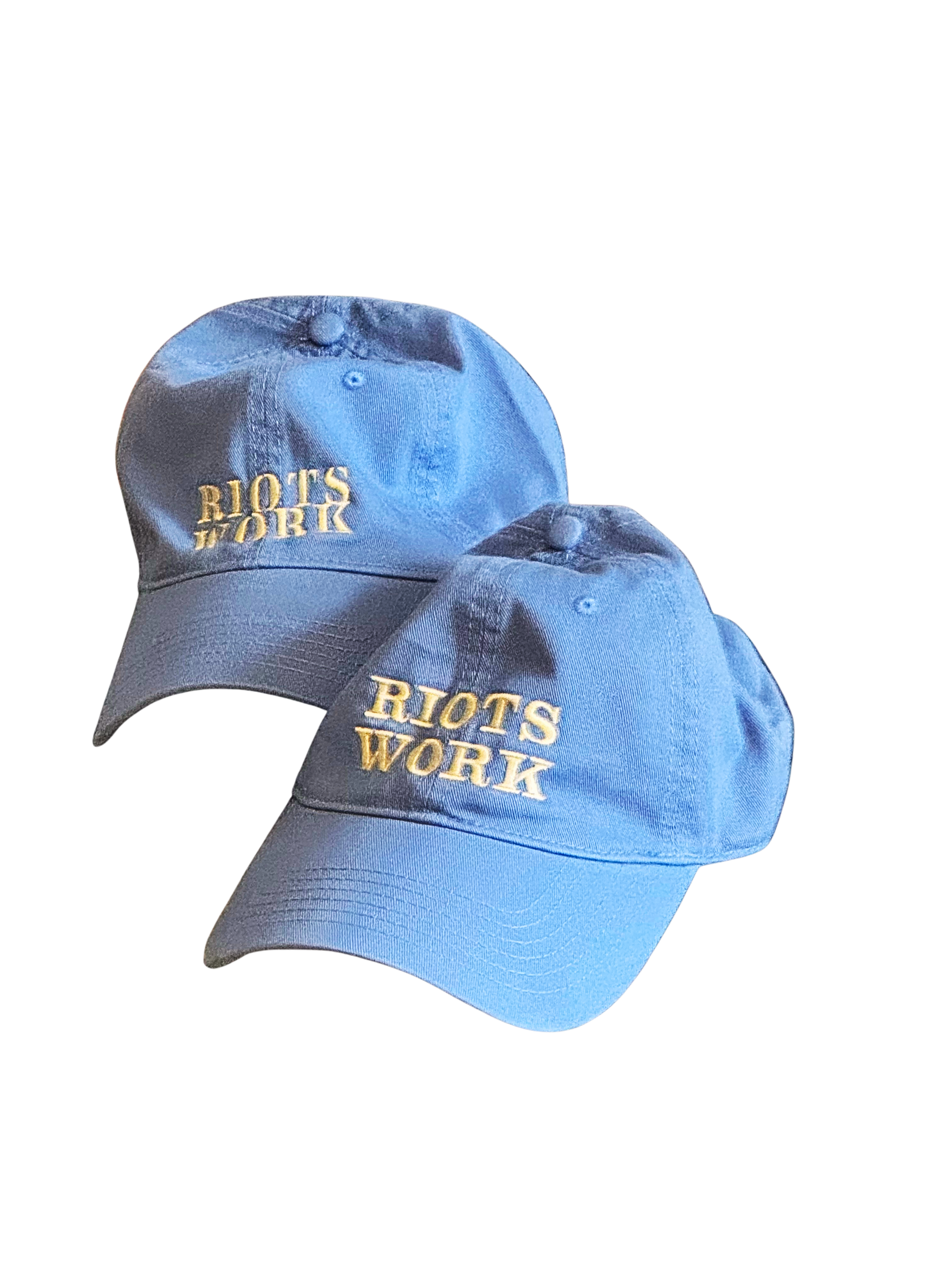 Three blue baseball caps with yellow embroidered text that reads "RIOTS WORK" on the front, arranged with some overlapping.