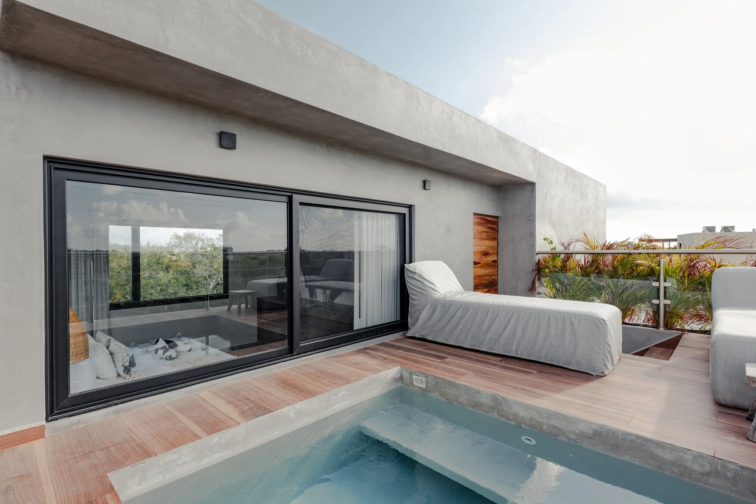 Modern rooftop patio with outdoor seating, potted plants, and sliding glass doors leading to indoor space.