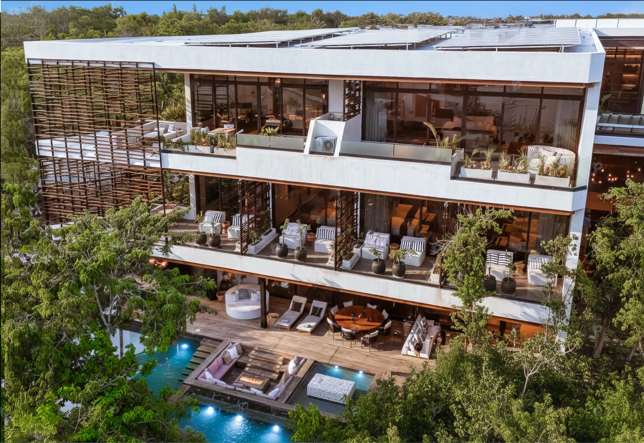 A modern multi-story house with balconies, outdoor furniture, and a swimming pool surrounded by trees and greenery.