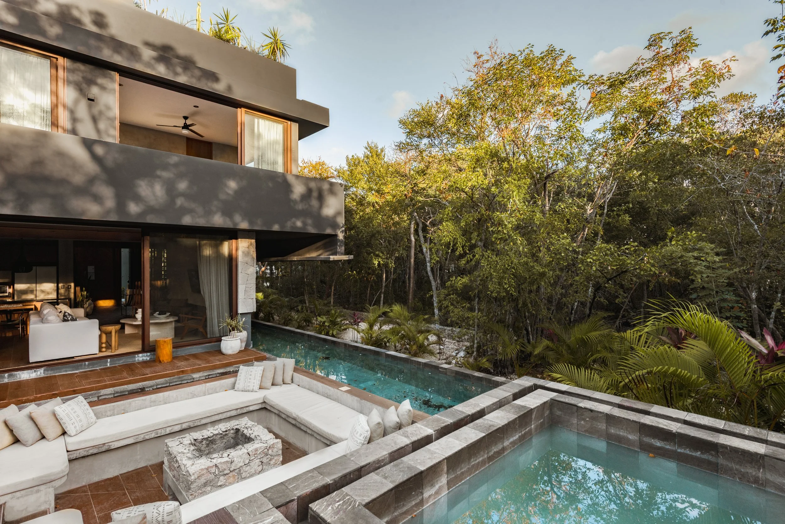 Backyard with a modern house, outdoor pool, and lush green trees.