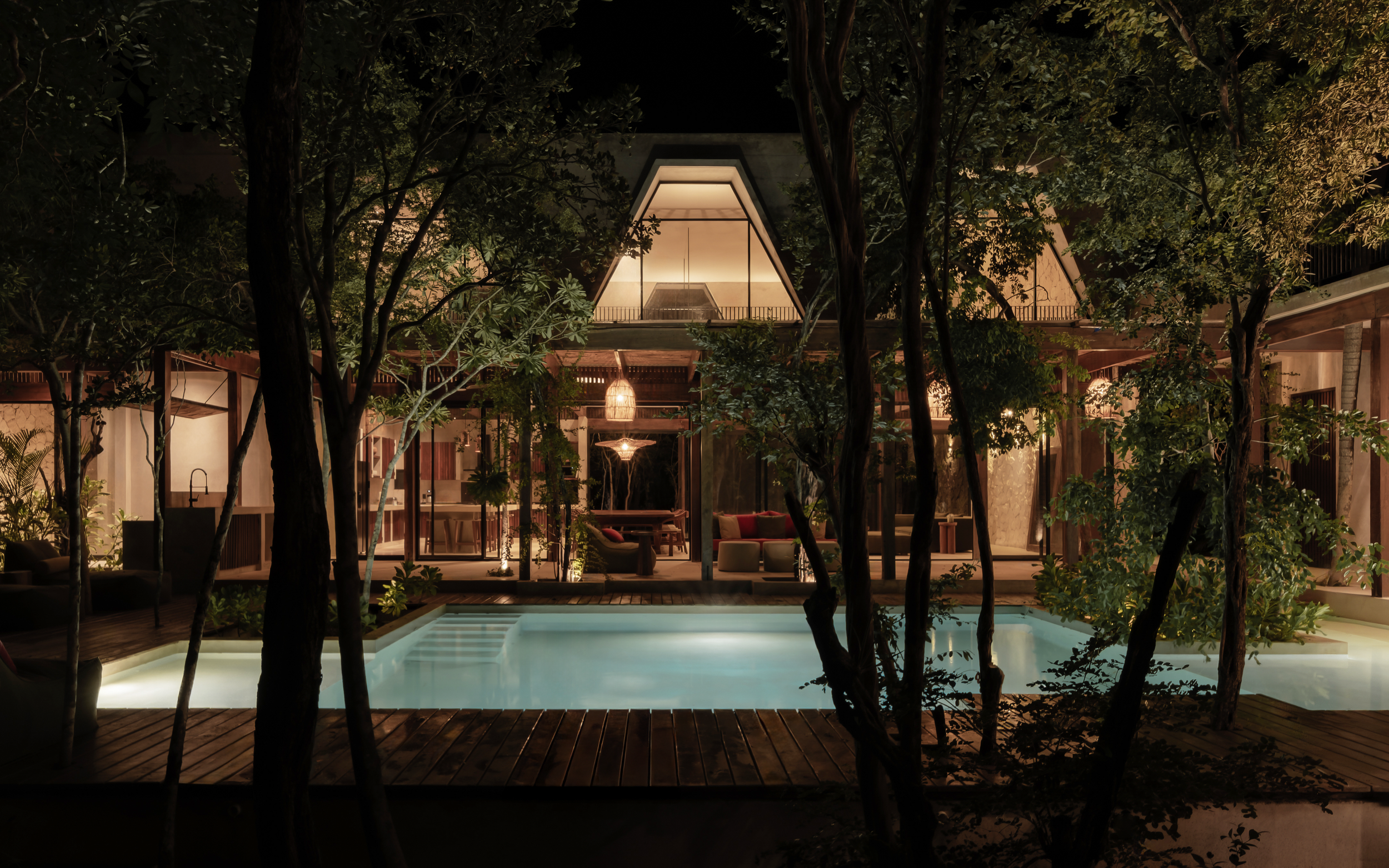 Night view of a modern house with an illuminated interior, surrounded by trees, with a swimming pool in the foreground.