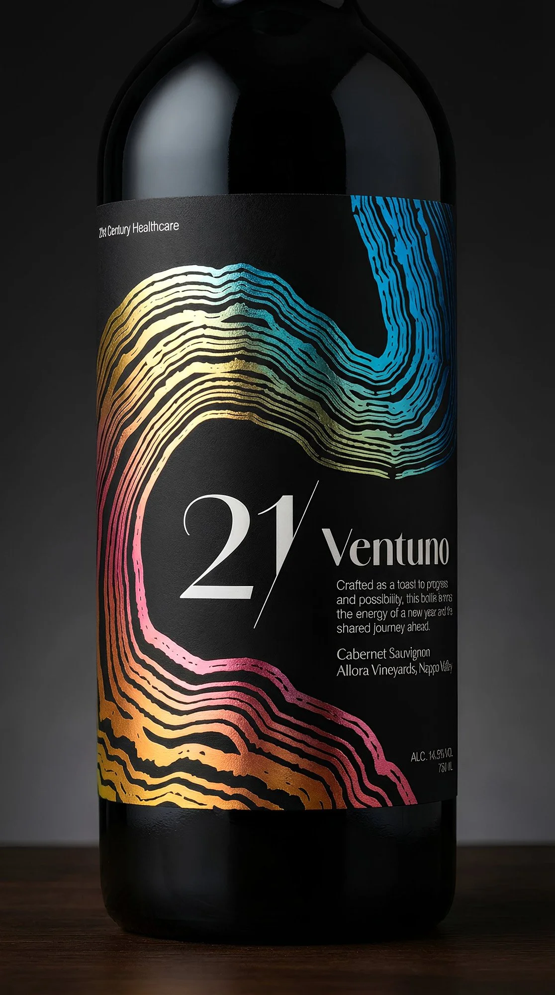 A black wine bottle with a colorful, wavy abstract label, featuring blue, yellow, and pink lines. The label reads "21/ Ventuno" and describes the wine as a Cabernet Sauvignon from Allora Vineyards in Nappa, with alcohol content of 14.6%. 