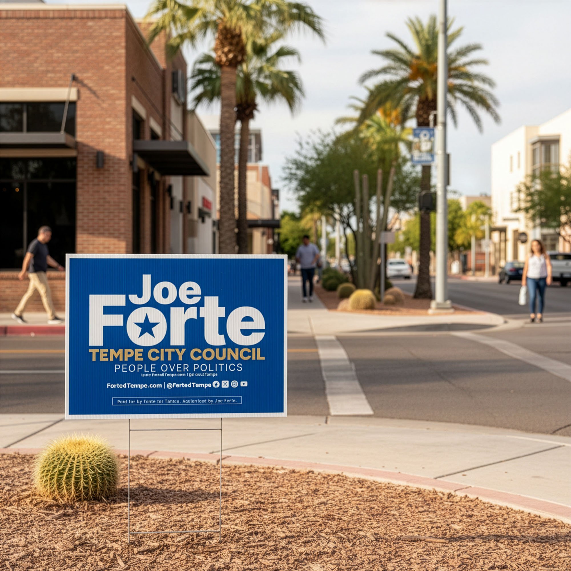 A political campaign sign for Joe Forte, running for Tempe City Council, placed in a small desert landscape with a round cactus. The background shows a city street with few pedestrians, palm trees, storefronts, and parked cars.