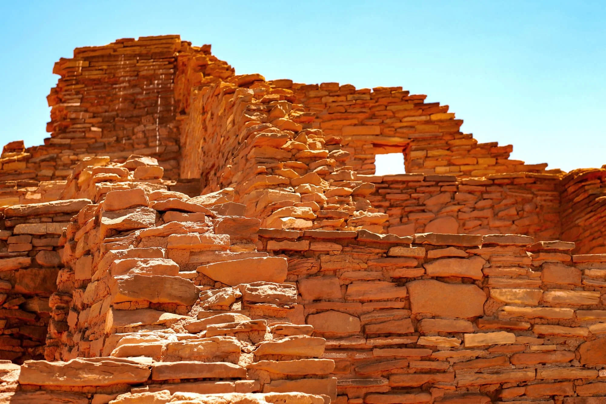 Close-up of ancient red brick ruins against a clear blue sky.