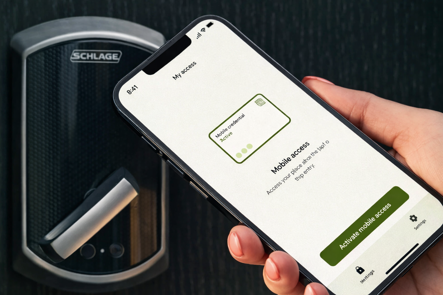 Person holding a smartphone displaying a mobile access app screen with a green 'Activate mobile access' button, in front of a black electronic door lock.