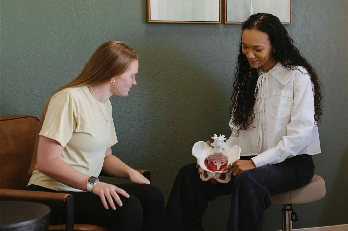 physical therapist holding a pelvic speaking to client about fertility support