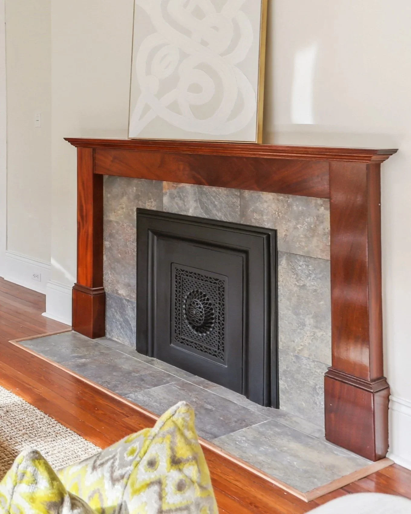 custom built mahogany fireplace with wooden mantel, stone surround, and black decorative cover, located in a room with hardwood flooring.