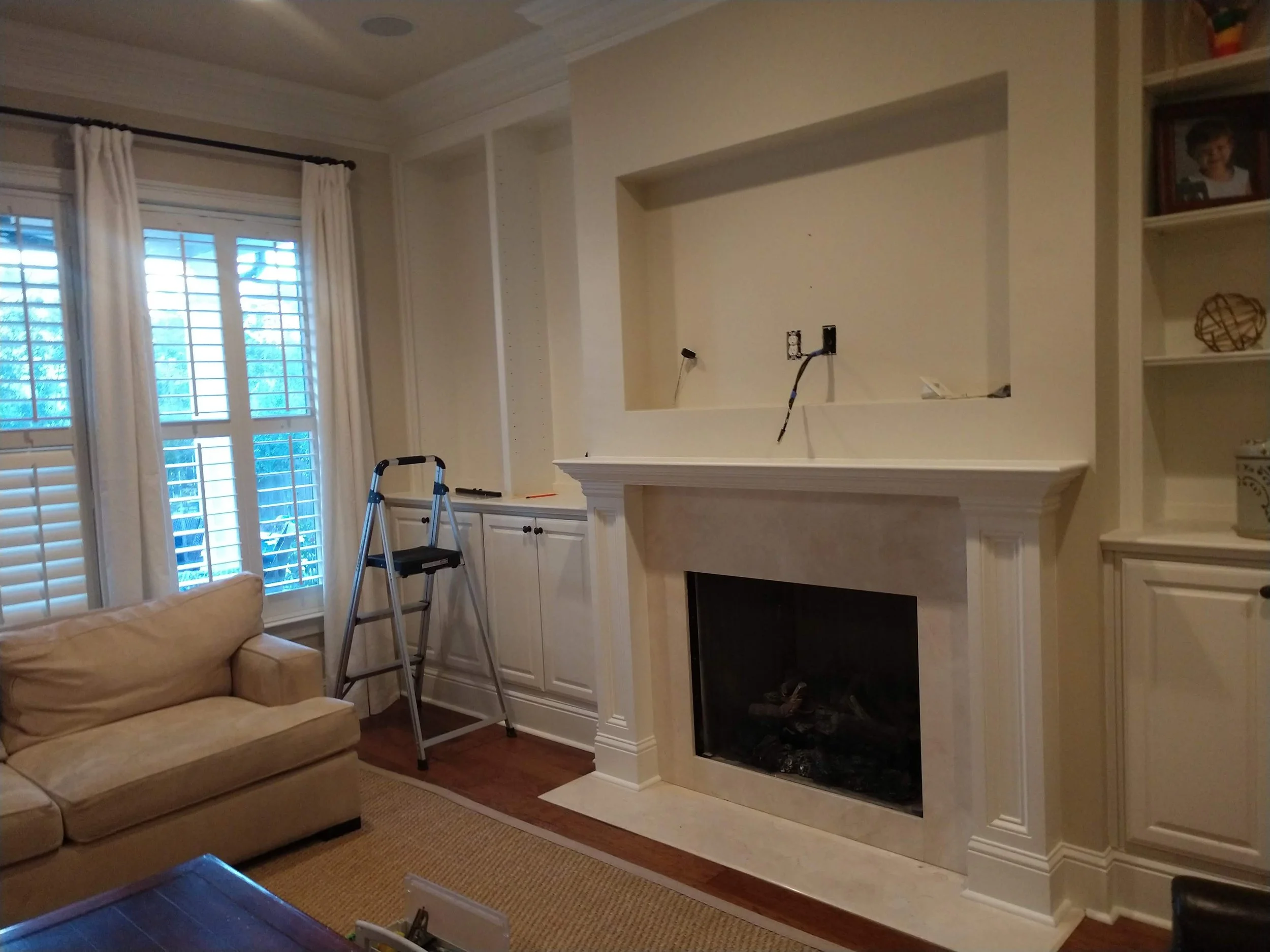 Living room with custom mantel and bookshelves. Features a recess over the mantel for a TV